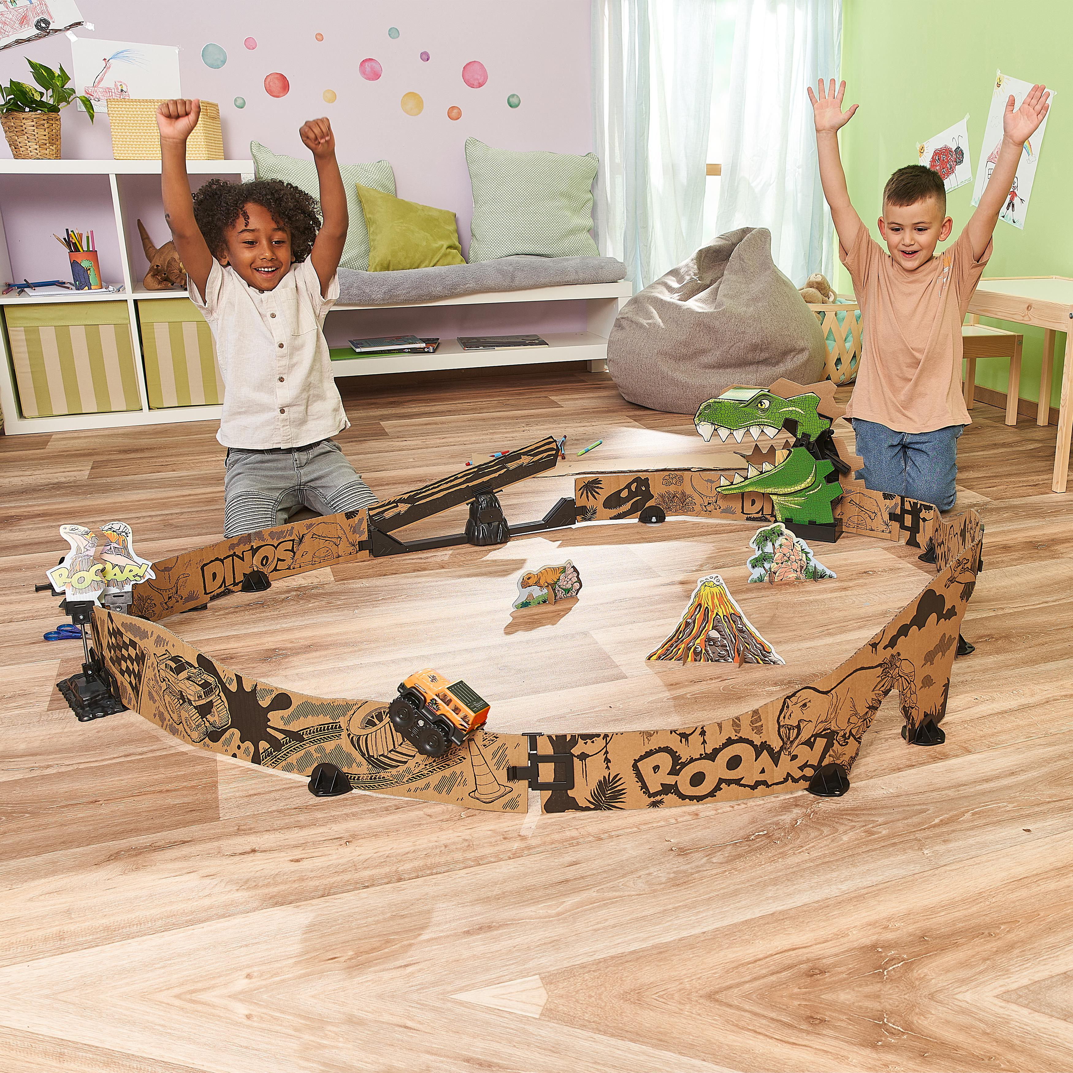 Zwei Kinder spielen mit einem Dinosaurier-Themen-Streckenset und heben aufgeregt ihre Hände.