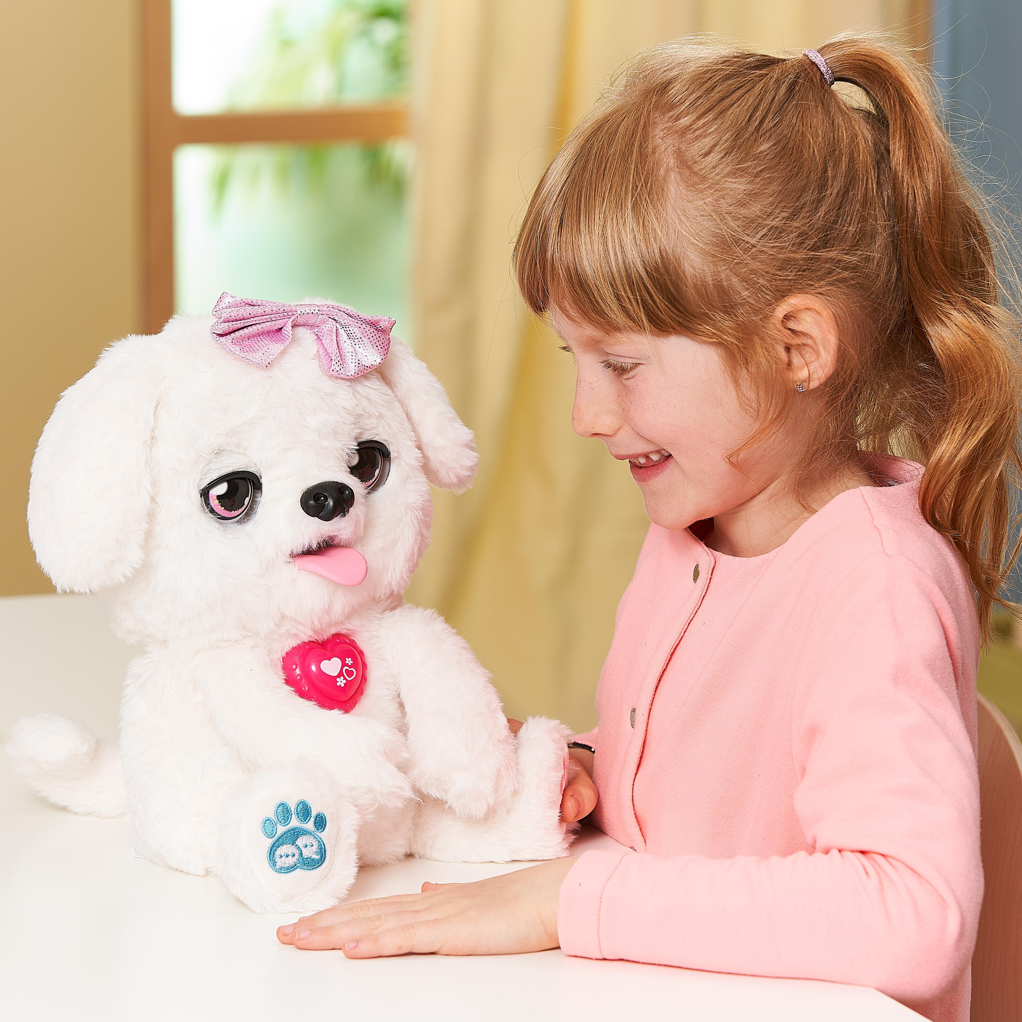 Ein Mädchen lächelt einen weißen Stoffhund mit rosa Schleife und heraushängender Zunge an.