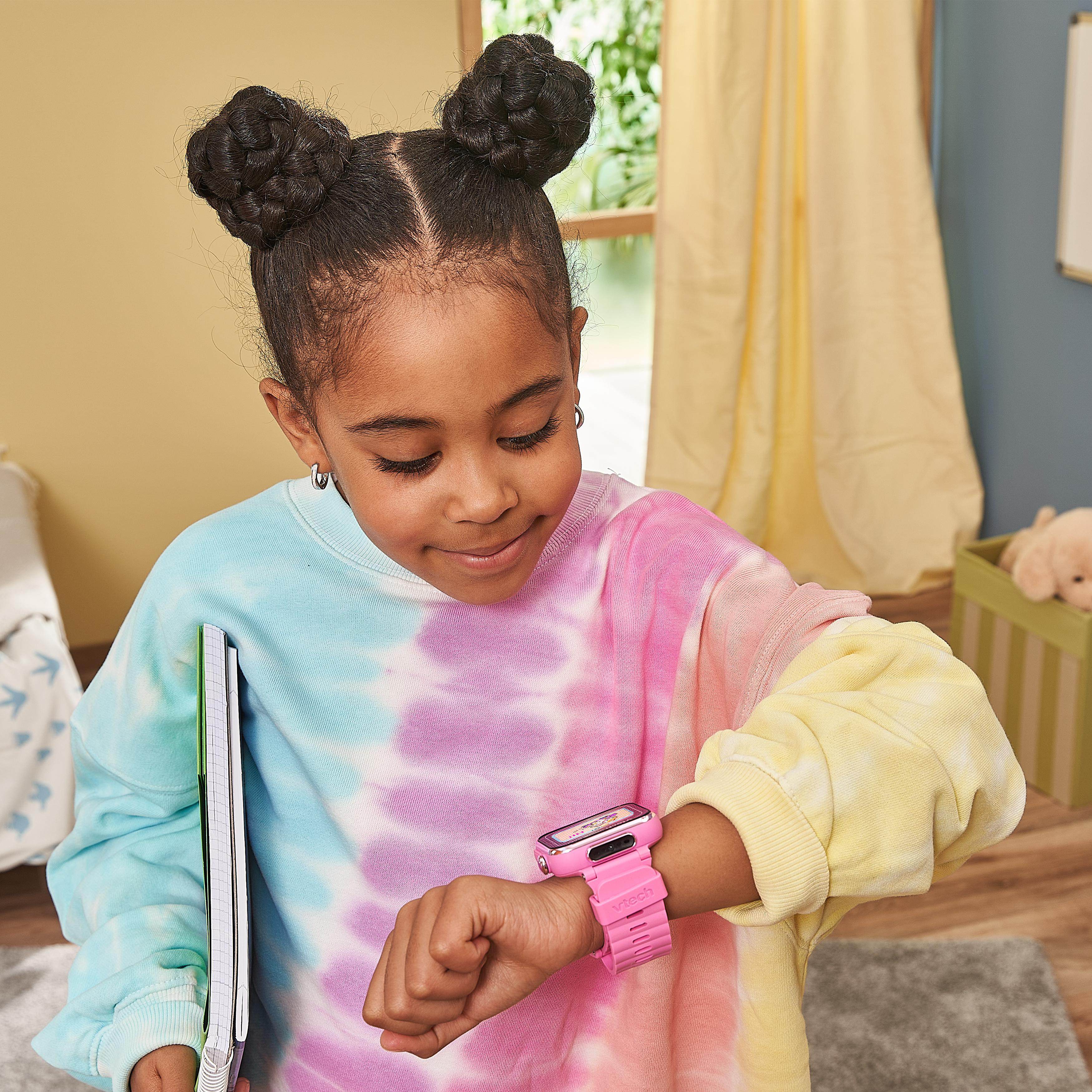 Ein Mädchen mit Space Buns, das eine rosa Smartwatch trägt, schaut auf den Bildschirm.