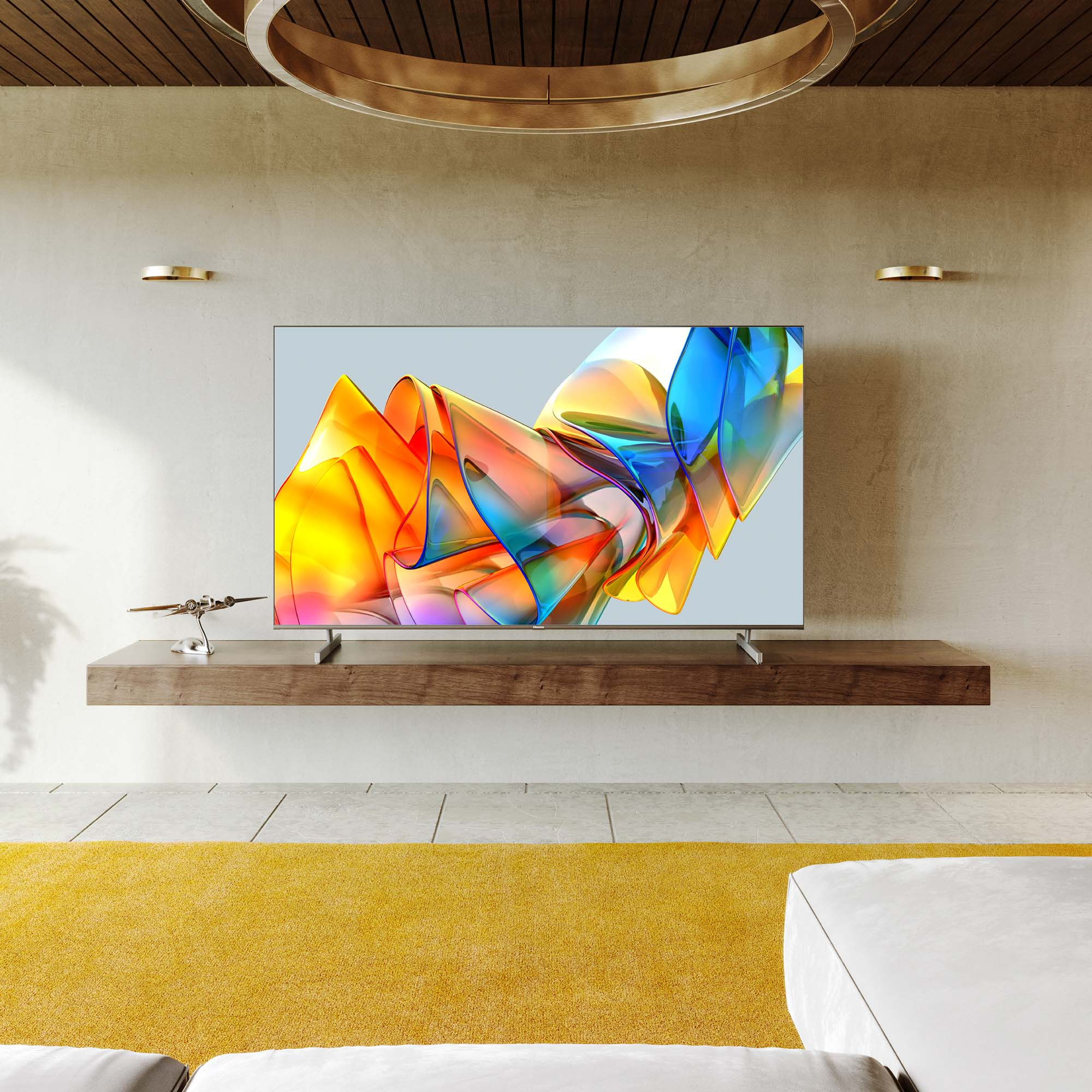 TV en un soporte de madera. Se muestra una obra de arte colorida. Una alfombra amarilla está en primer plano.