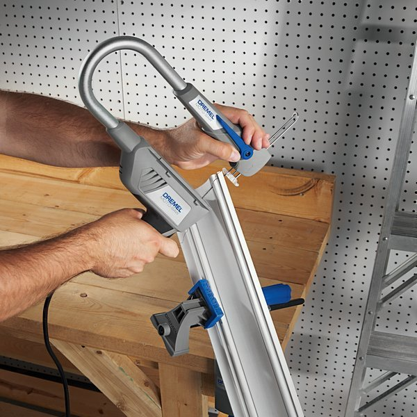 Személy Dremel fűrésszel fát vág. A fűrész használatban, a munkaasztal látható.