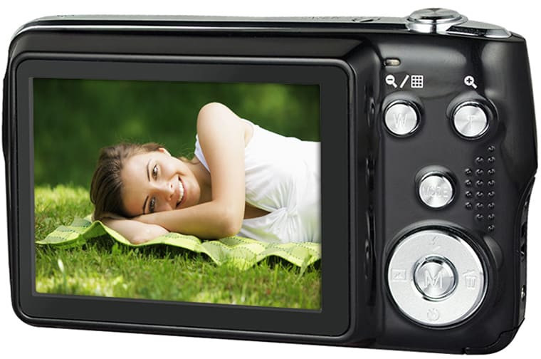 Een zwarte digitale camera, die een lachende vrouw op een groen grasveld toont.
