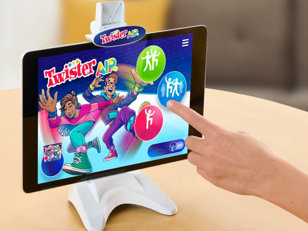 Tablet mit Twister Air-Spiel, Hand berührt Bildschirm. Zwei Charaktere werden gezeigt.