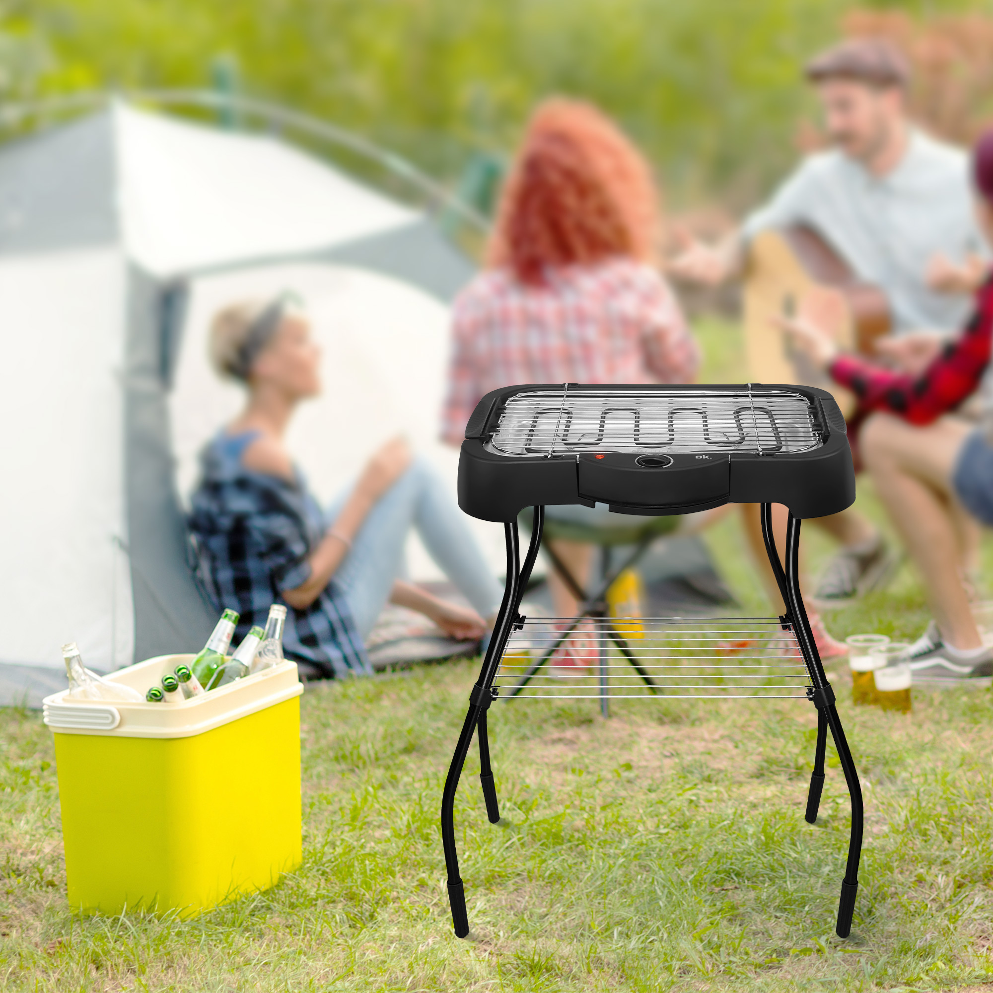 Ein schwarzer Grill auf einem Ständer, mit Lebensmitteln. Menschen und eine Kühlbox im unscharfen Hintergrund.