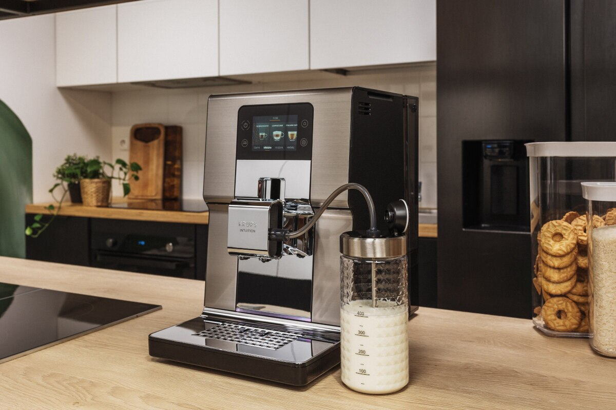 Nowoczesny ekspres do kawy ze zbiornikiem na mleko, ustawiony na drewnianym blacie.