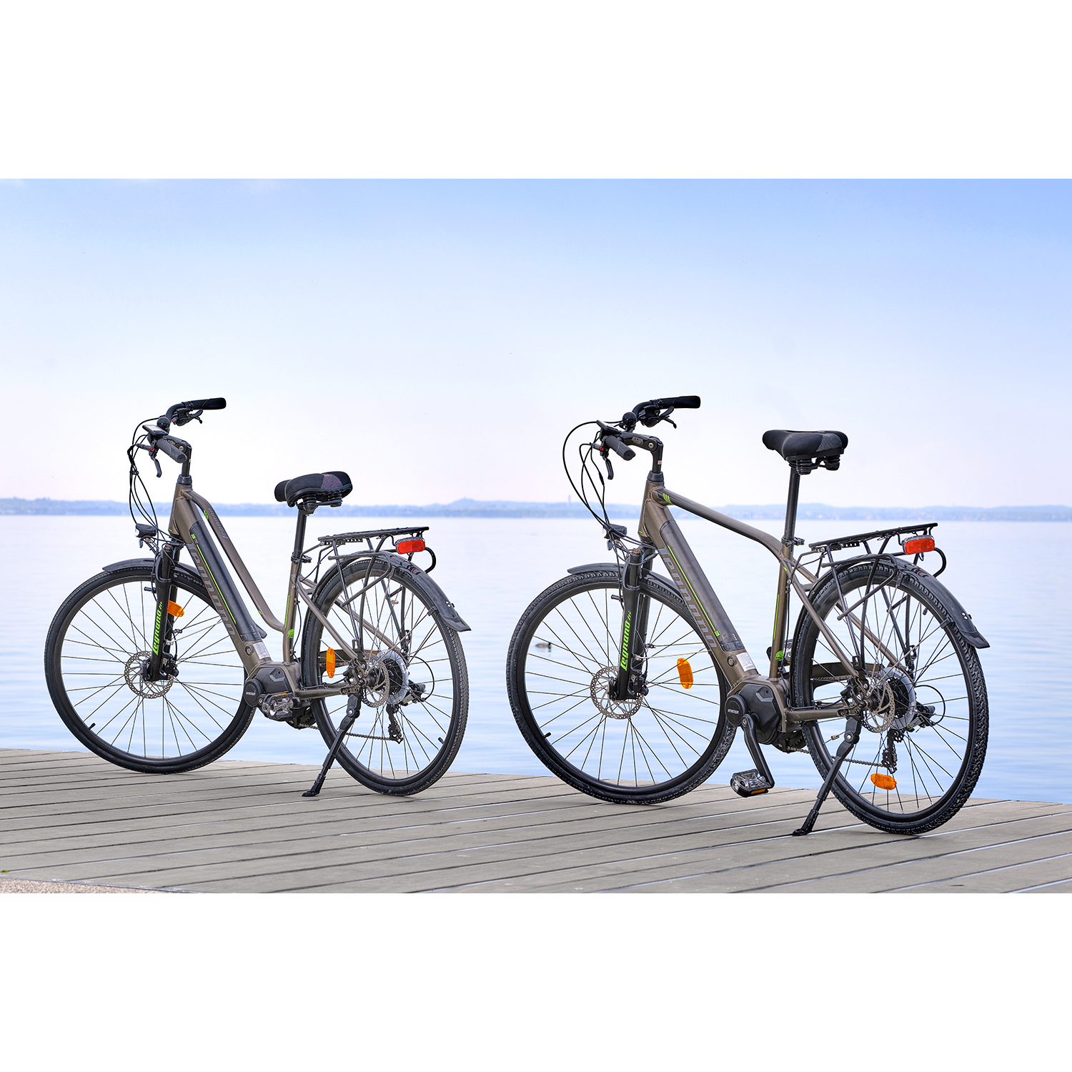Due biciclette su una piattaforma di legno che si affaccia su un lago. Le bici sono grigie e nere.