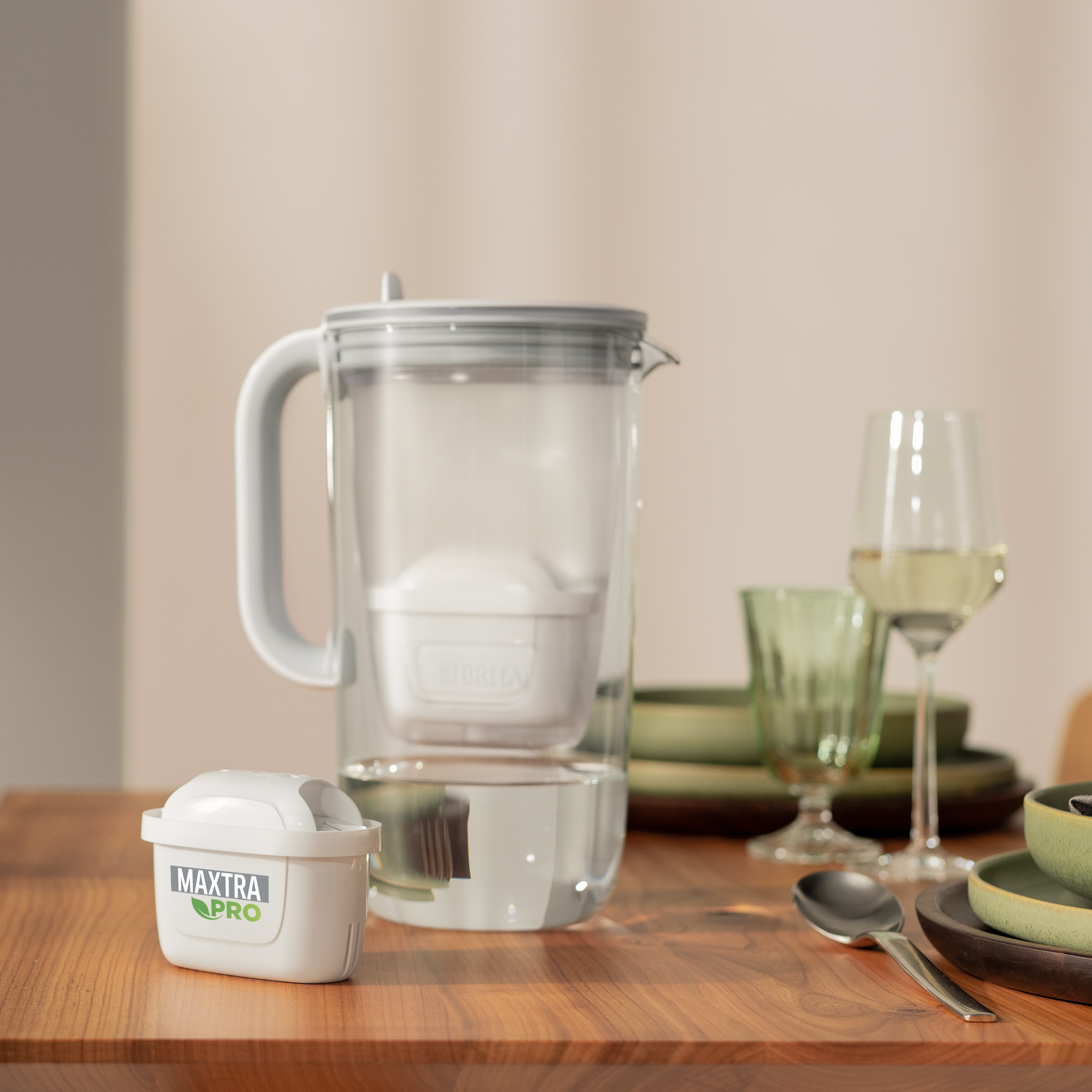 Ein Wasserfilterkrug mit Filter innen und einem separaten Filter auf einem Holztisch.