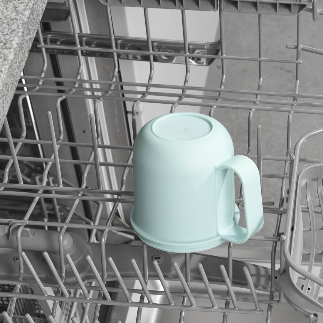 Un mug bleu clair à l'intérieur d'un lave-vaisselle, à l'envers, dans un cadre de cuisine.