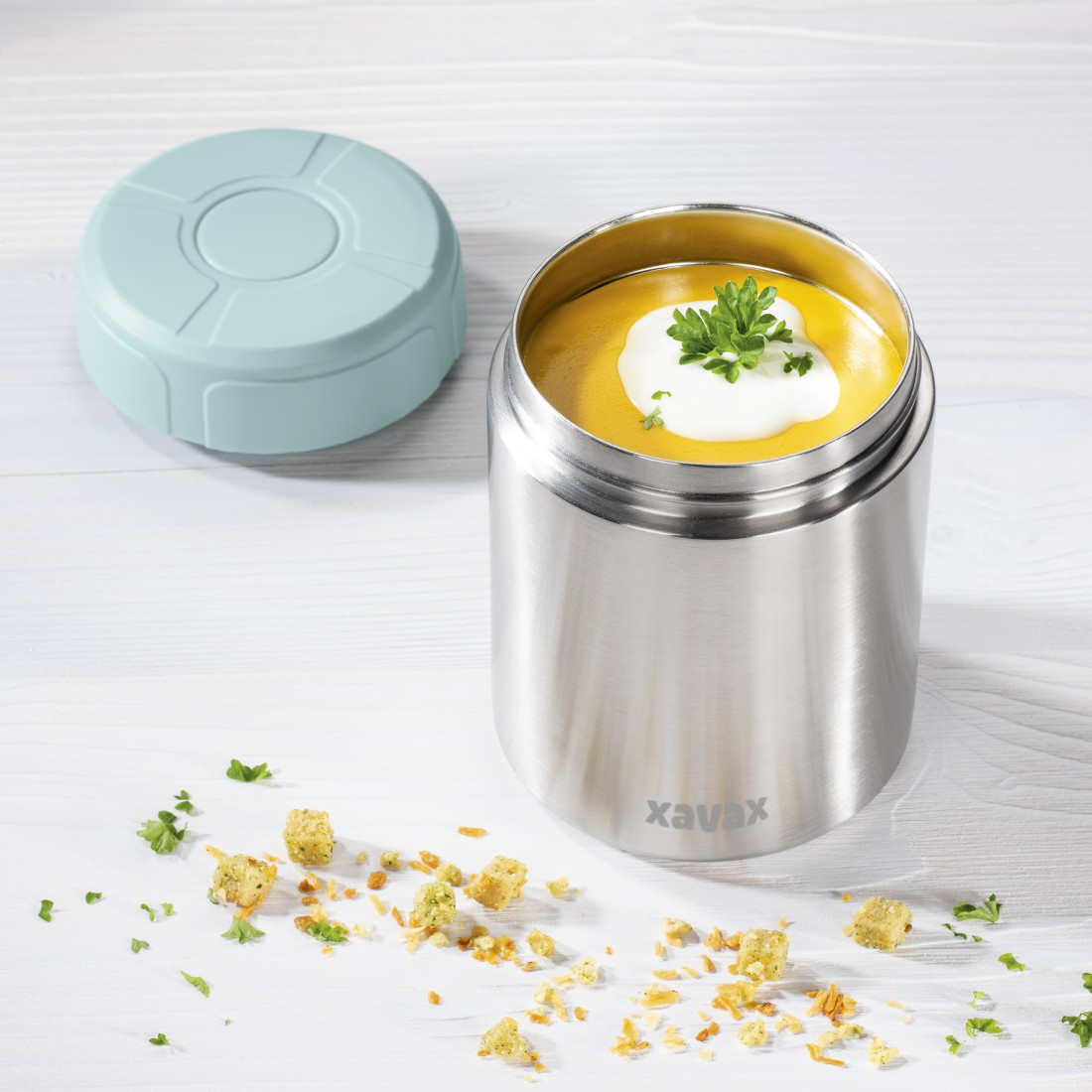 Un récipient thermique en acier inoxydable avec de la soupe, des croûtons et un couvercle.
