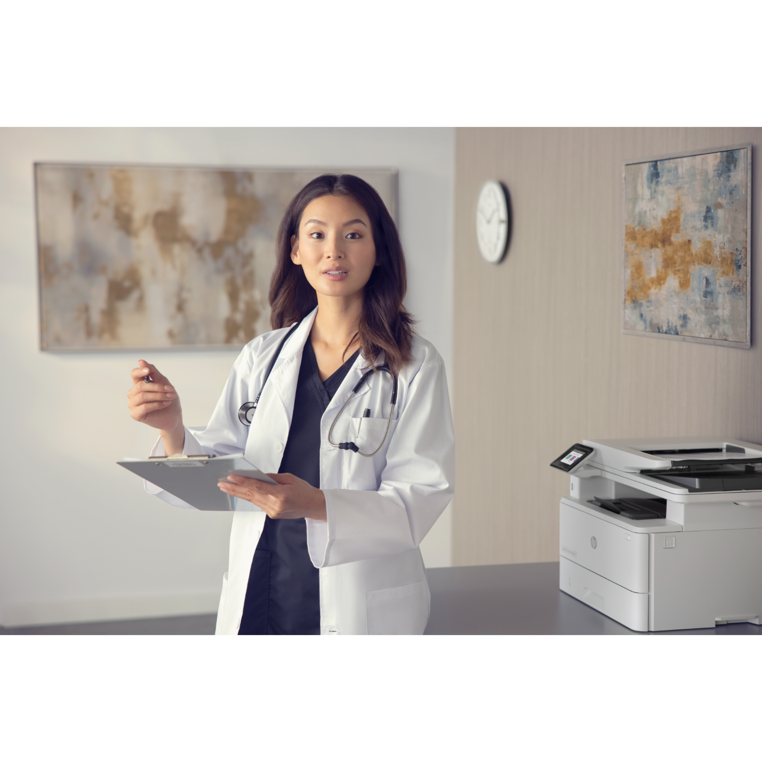 A doctor in a white coat is holding a clipboard and pointing in a medical office.