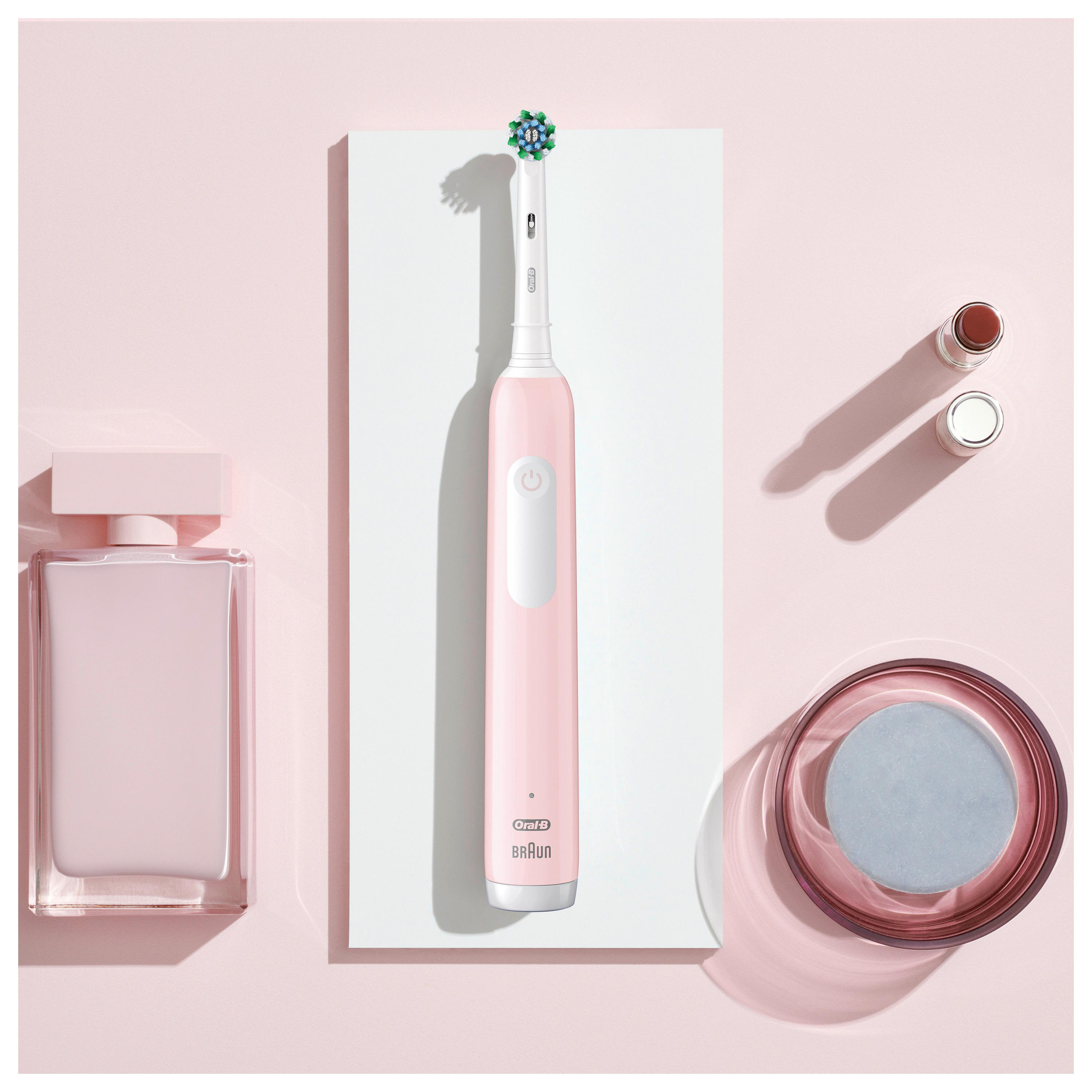 Pinke elektrische Zahnbürste, Parfüm, Lippenstift und Glas Wasser auf Pink.