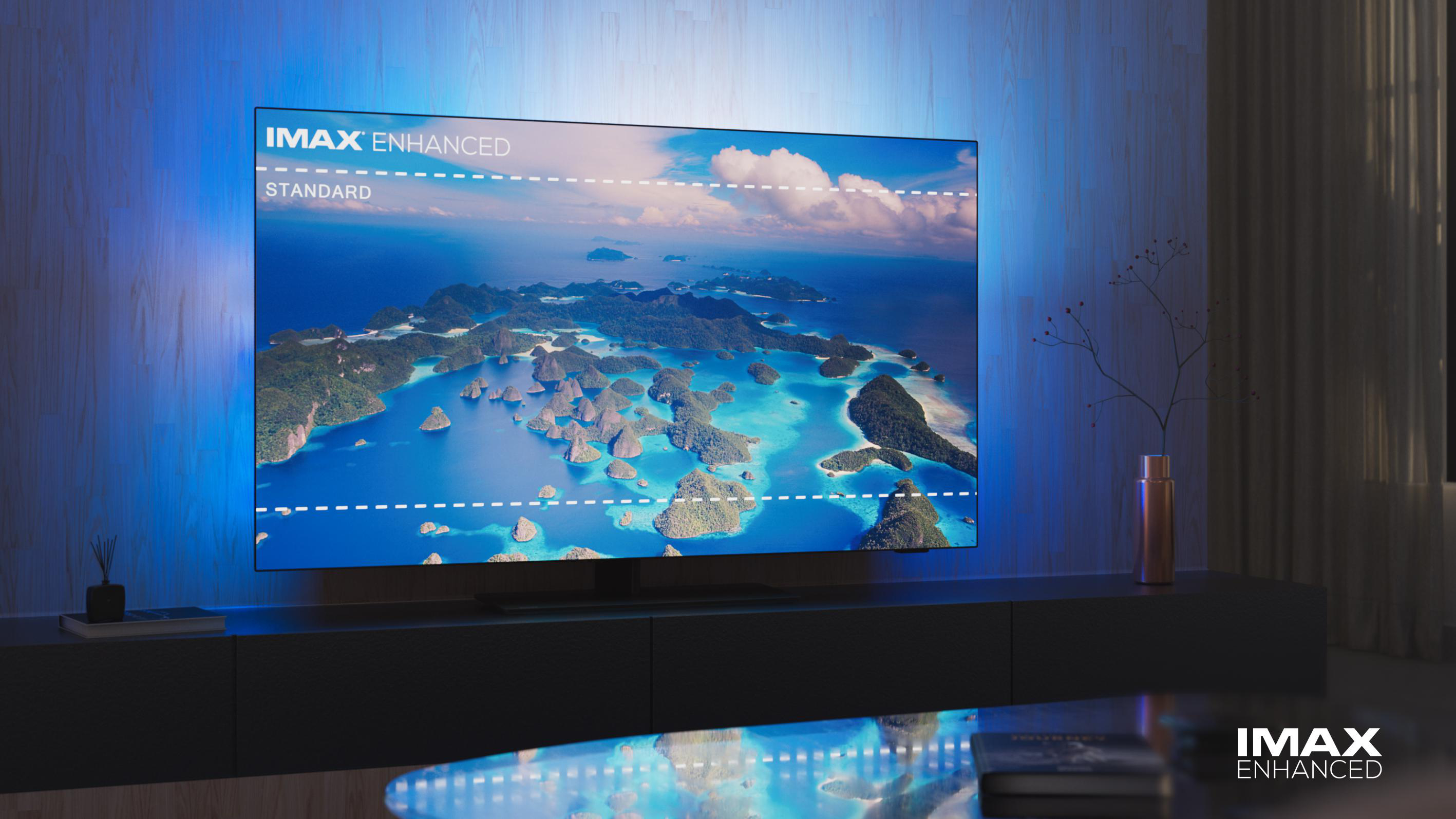 Ein großer Bildschirm-TV, der eine tropische Landschaft zeigt. Der Fernseher steht auf einem dunklen Ständer in einem modernen Wohnzimmer.