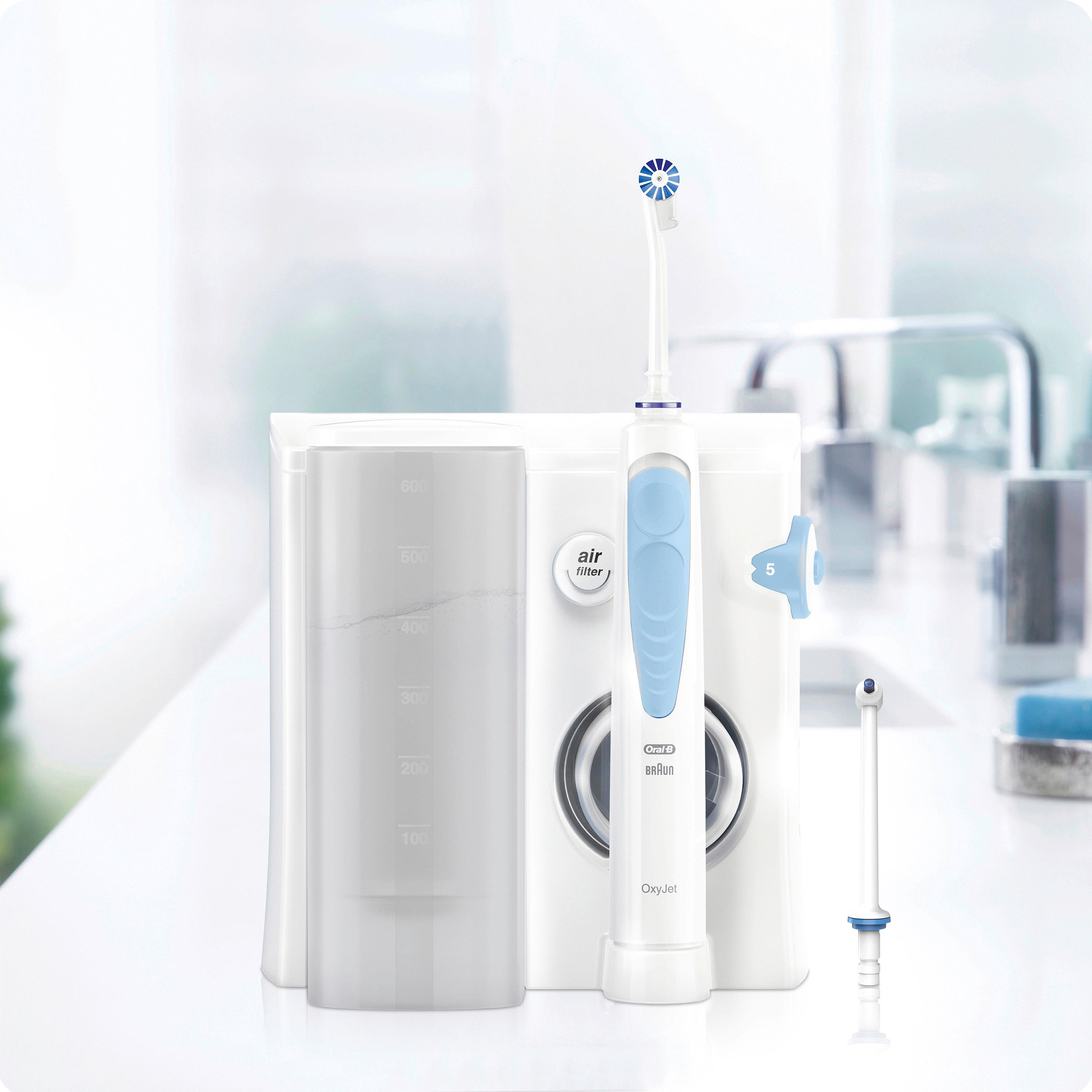 Elektrische Zahnbürste und Munddusche-Set. Weiß mit blauen Akzenten, auf weißer Oberfläche platziert.