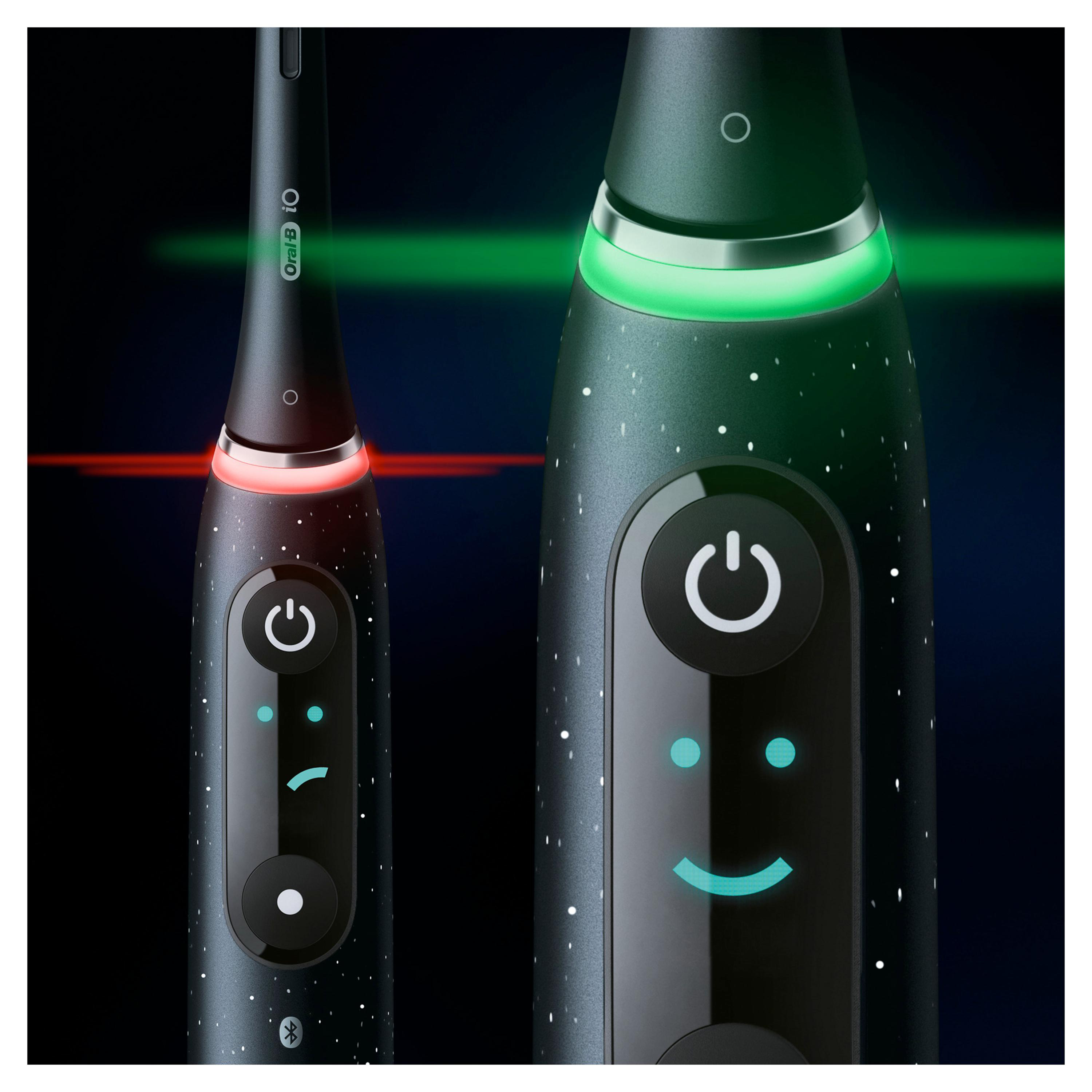Zwei elektrische Zahnbürsten nebeneinander. Eine zeigt ein grünes Licht, die andere ein rotes Licht.