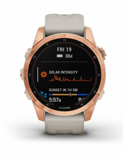 Smartwatch z okrągłą, różowo-złotą kopertą, wyświetlający godzinę, datę i dane dotyczące intensywności słonecznej.
