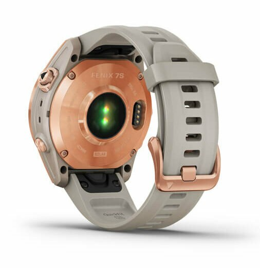 Smartwatch Garmin Fenix 7S, widok z tyłu. Ma szary pasek i różowo-złotą ramkę. Zielone światło z czujnika.