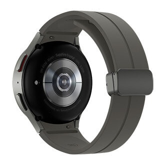 Tył szarego smartwatcha z metalową obudową i stykami ładowania.