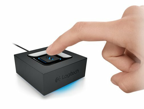 Ręka naciskająca czarne urządzenie Logitech, czarne pudełko, niebieskie światło.