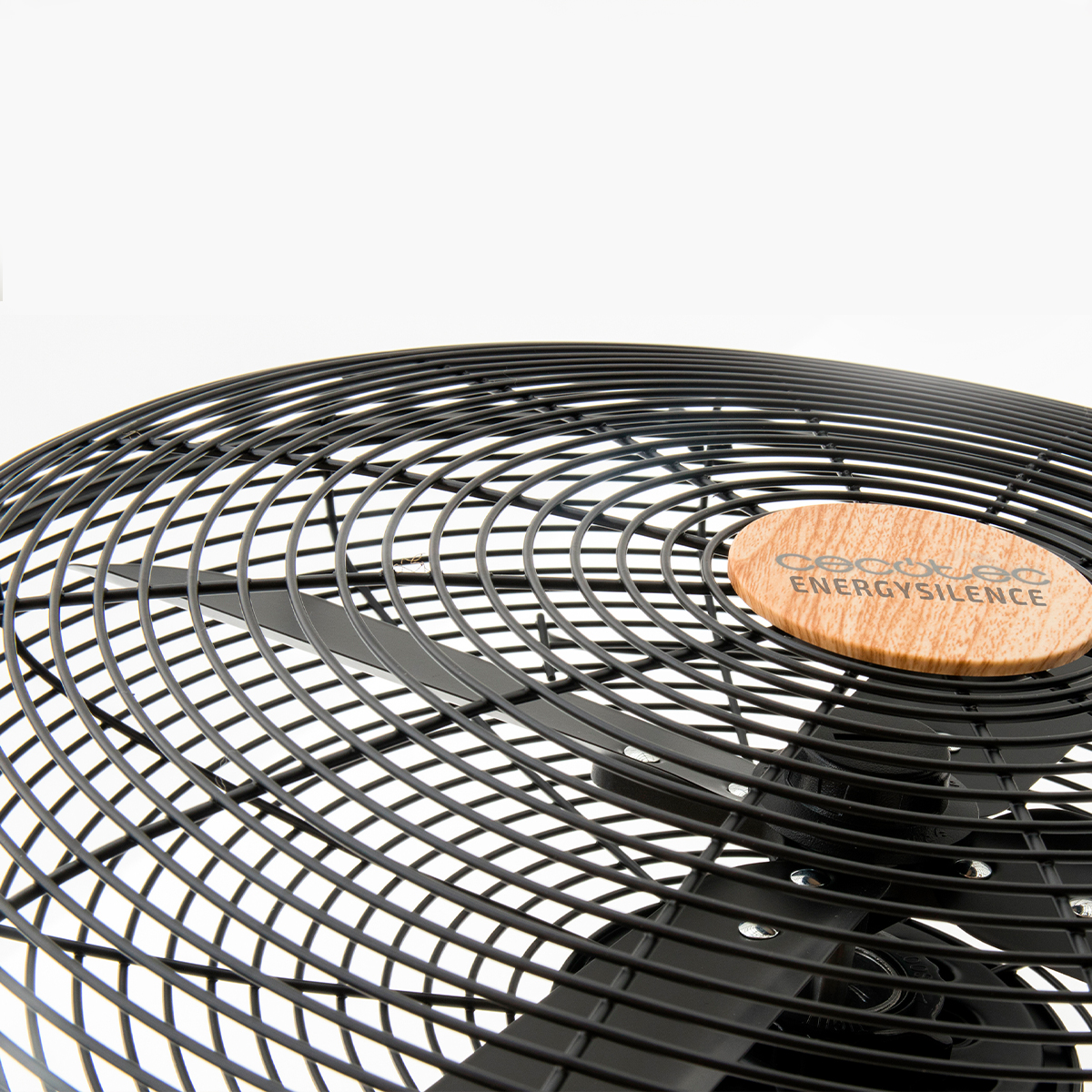 Primer plano de un ventilador negro con rejilla metálica y logo de madera.
