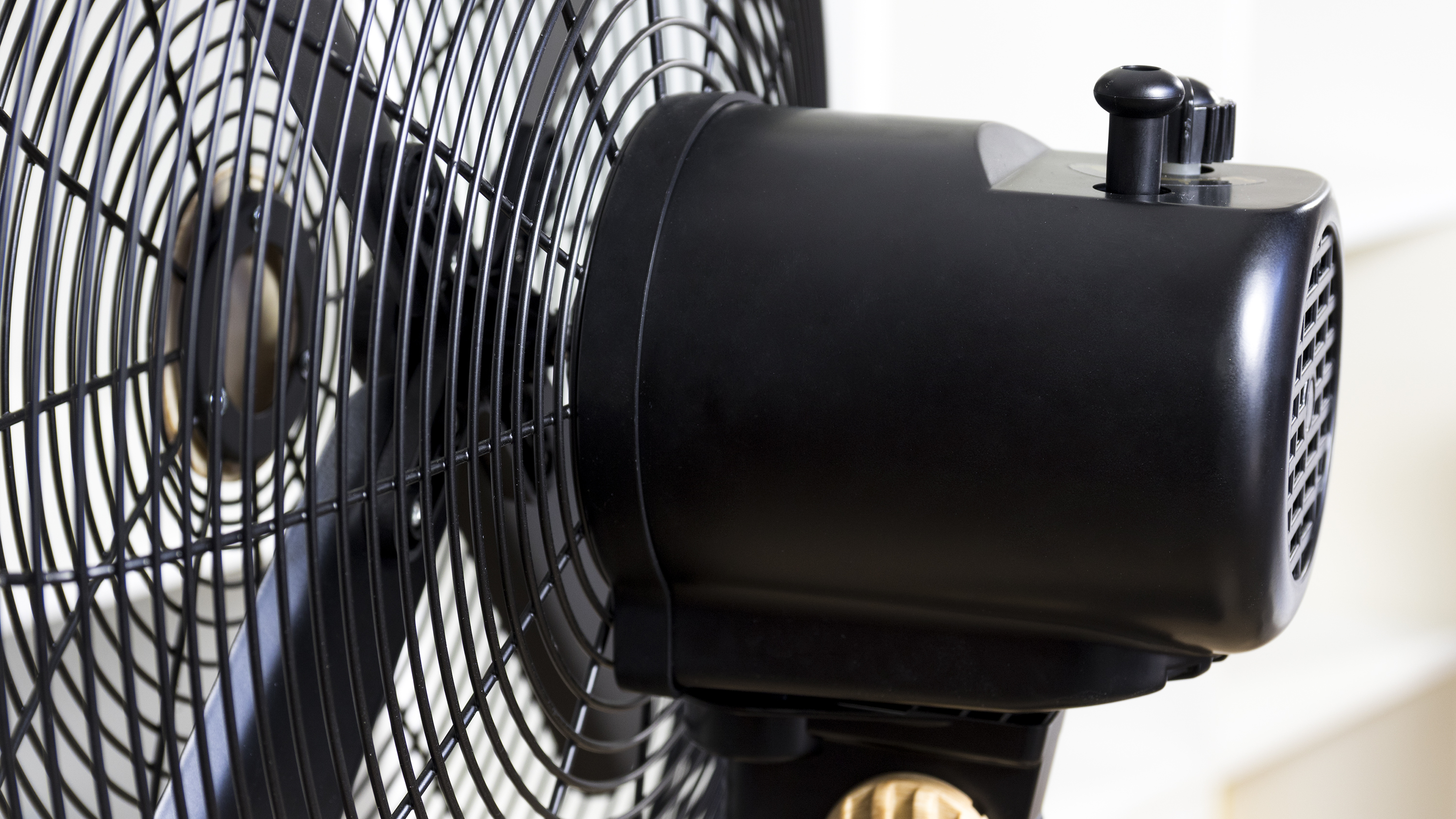 Primer plano de un ventilador eléctrico negro con una jaula protectora.