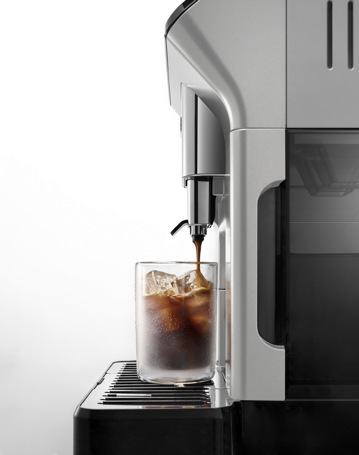 Máquina de espresso vertiendo café en un vaso lleno de hielo. Fondo blanco.