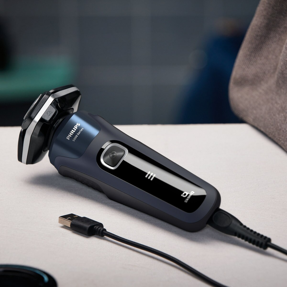 Niebiesko-czarna golarka elektryczna z podłączonym kablem USB, umieszczona na stole.