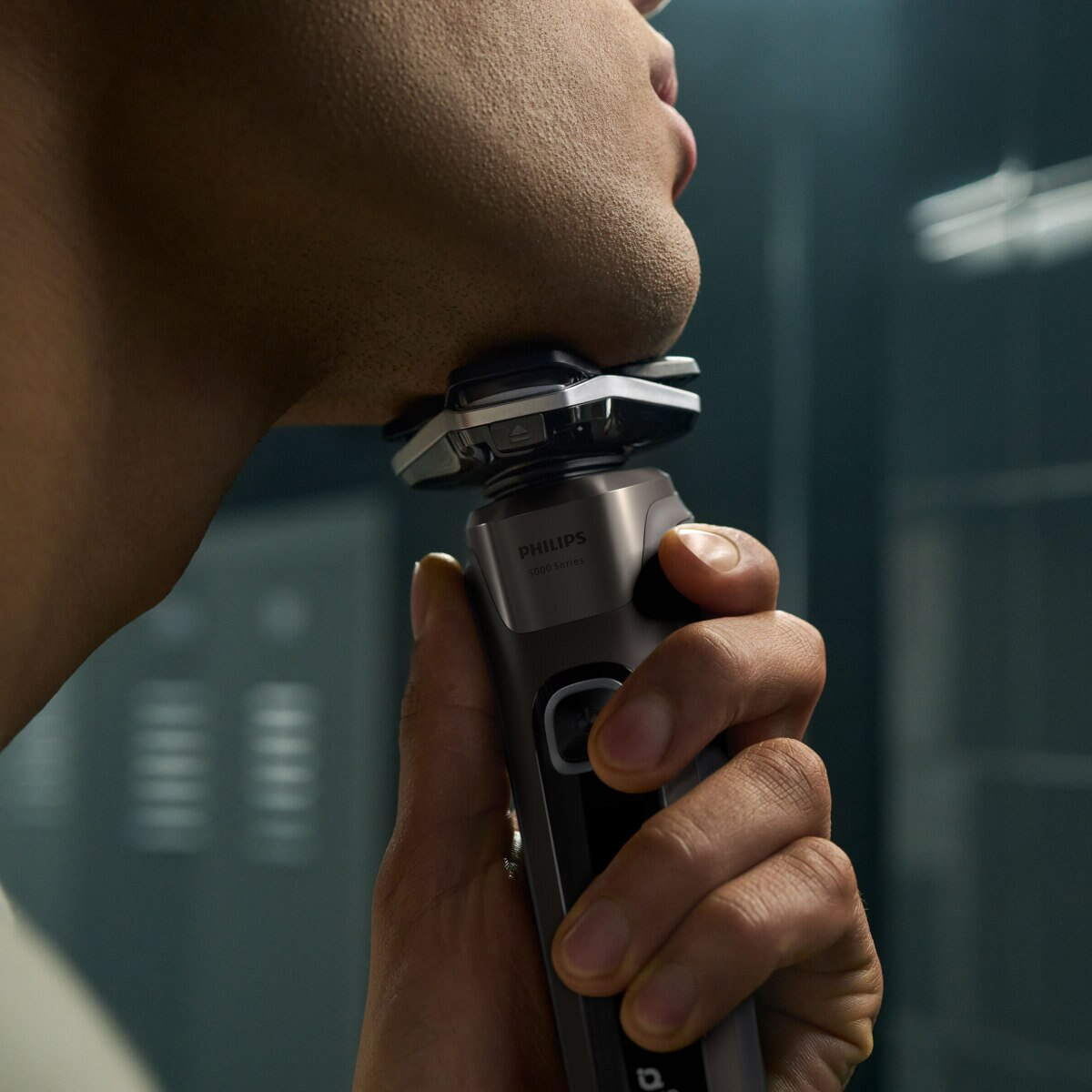 Mężczyzna używający golarki Philips na twarzy, zbliżenie z ostrością na golarce.