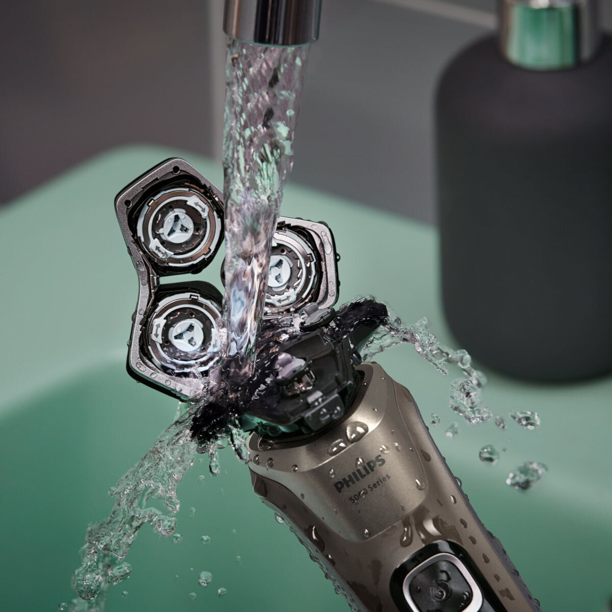 Golarka elektryczna pod bieżącą wodą, z trzema widocznymi głowicami.