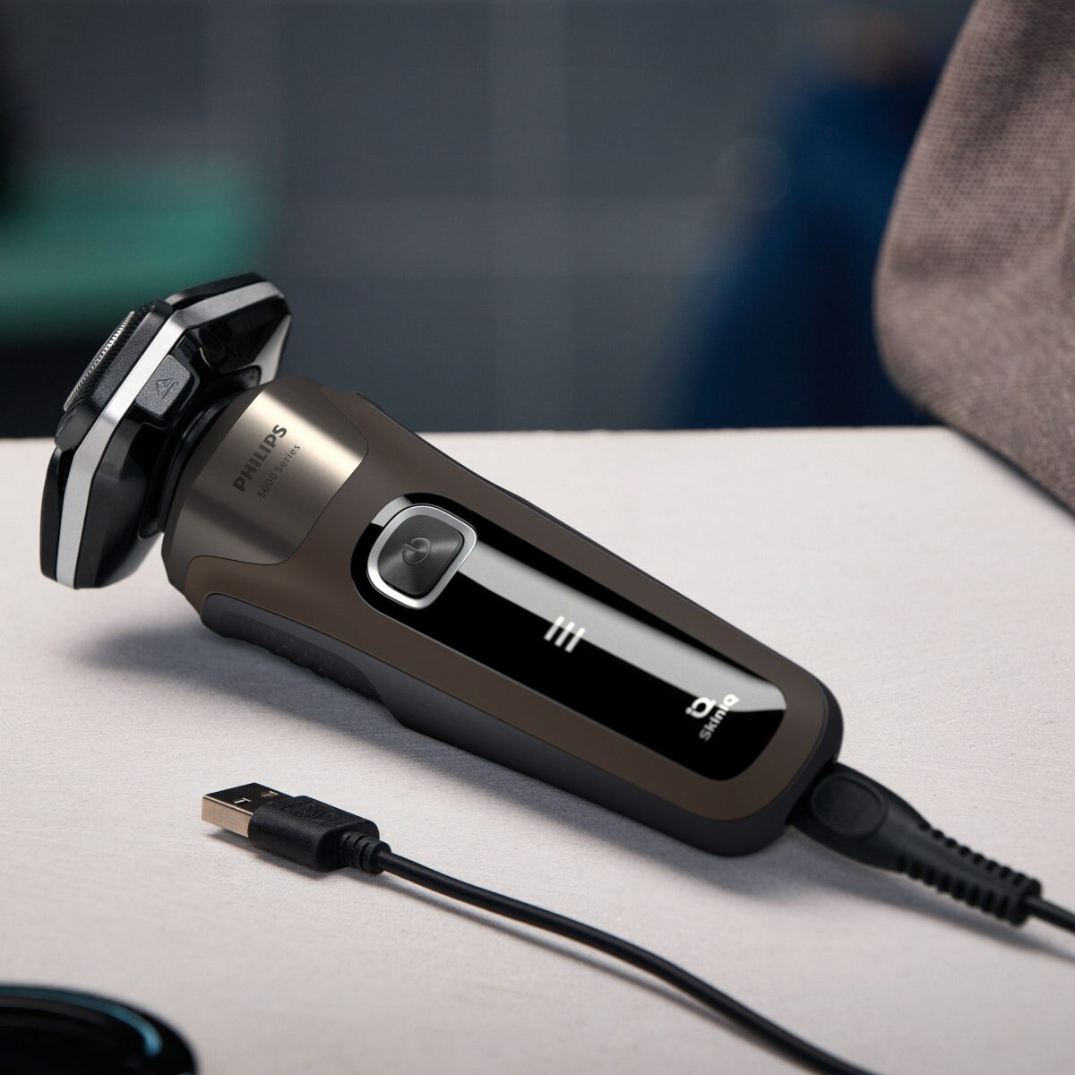 Czarna i brązowa golarka elektryczna z kablem do ładowania USB na stole.