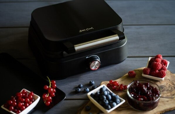 Czarny gofrownica z jagodami i dżemem na drewnianej desce, czarne talerze.