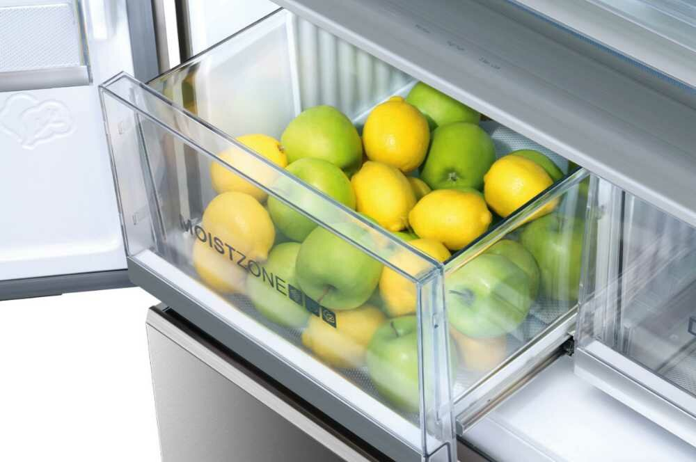 Szuflada lodówki wypełniona zielonymi jabłkami, żółtymi cytrynami, w pojemniku 'Moist Zone'.