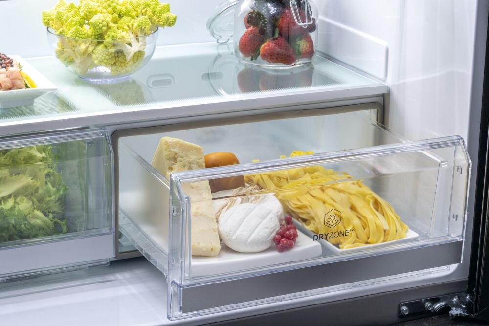 Szuflada lodówki wypełniona serem, makaronem i innymi produktami spożywczymi.