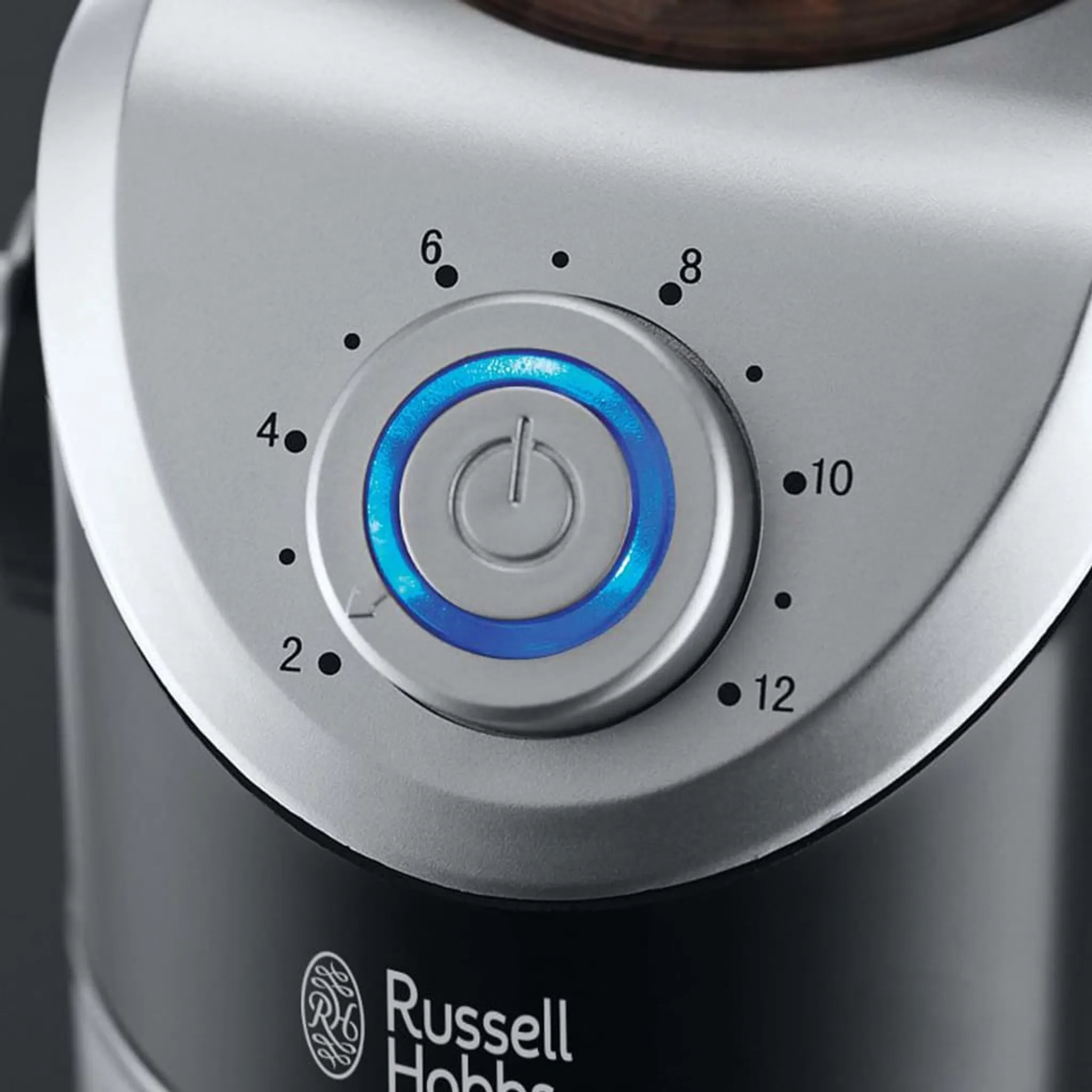 Egy Russell Hobbs kávédaráló bekapcsoló tárcsájának közeli képe kék fénnyel.
