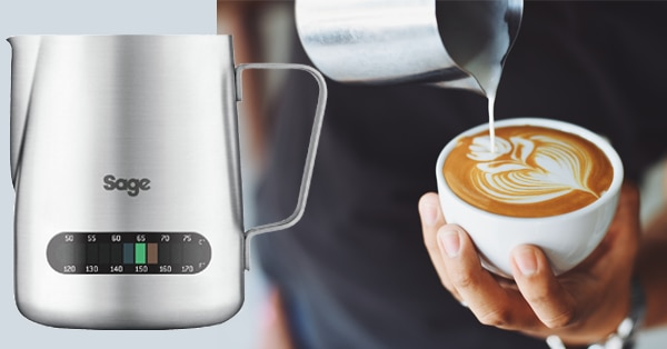 Ezüst kávéskanna hőmérővel, mellette egy kéz, ami tejet önt egy latte-ba.