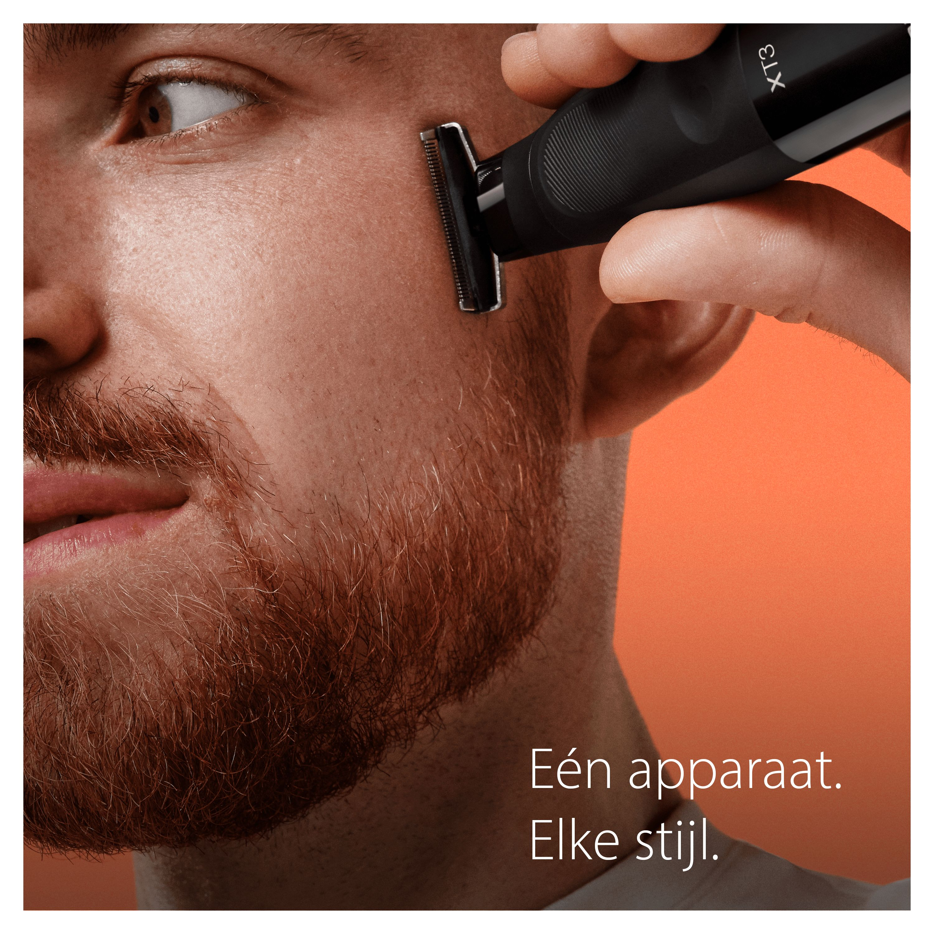 Man shaving his cheek with a black trimmer against an orange background.