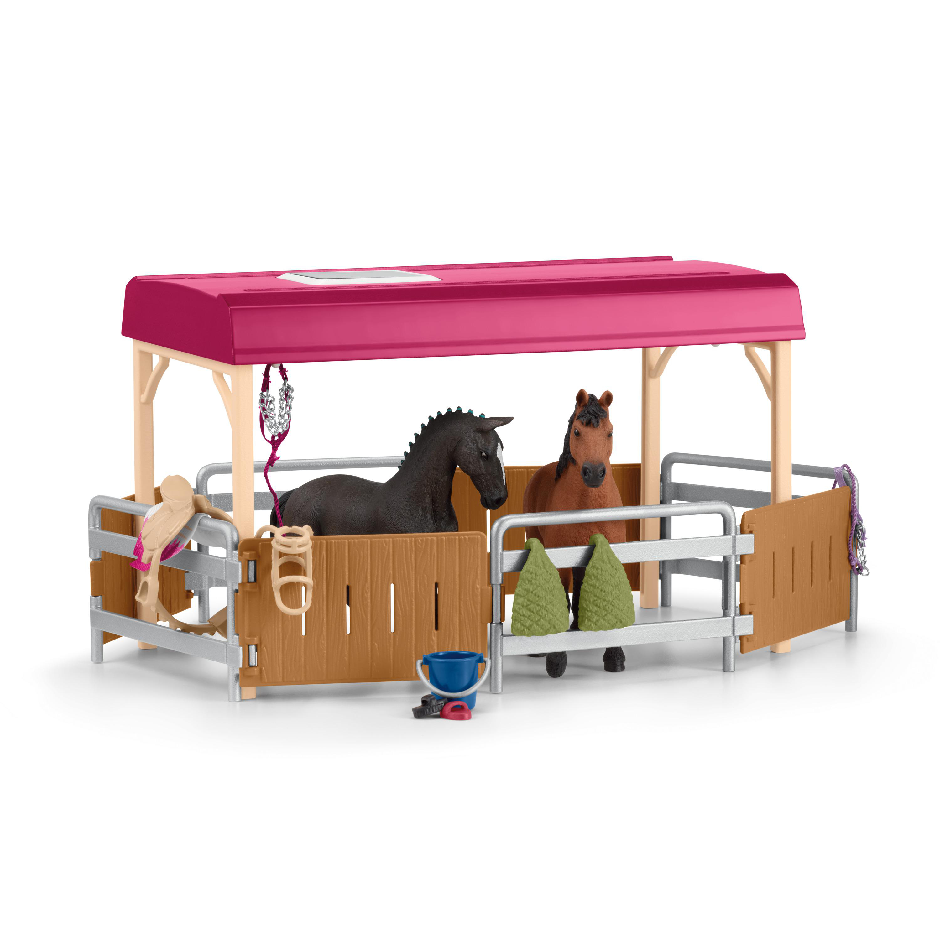 Ein Spielzeug-Pferdestall mit zwei Spielzeugpferden. Der Stall ist braun und rosa.