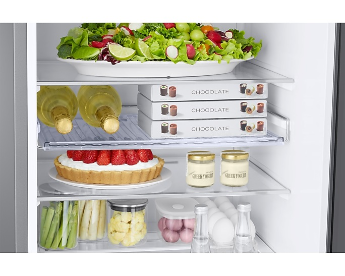 Hűtő belseje ételekkel: saláta, csokoládédobozok, torta, joghurt, spárga, tojás.