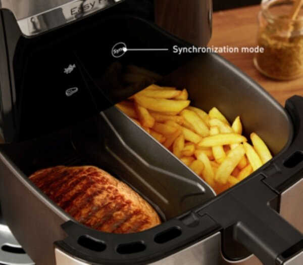 Frytownica powietrzna z frytkami i stekiem w środku. Frytownica jest otwarta.