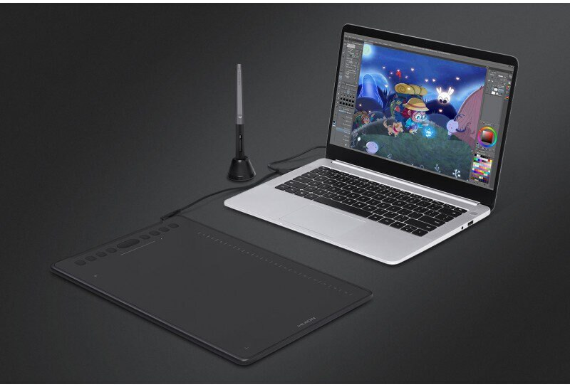 Tablet graficzny podłączony do laptopa, obok rysika, na czarnej powierzchni.