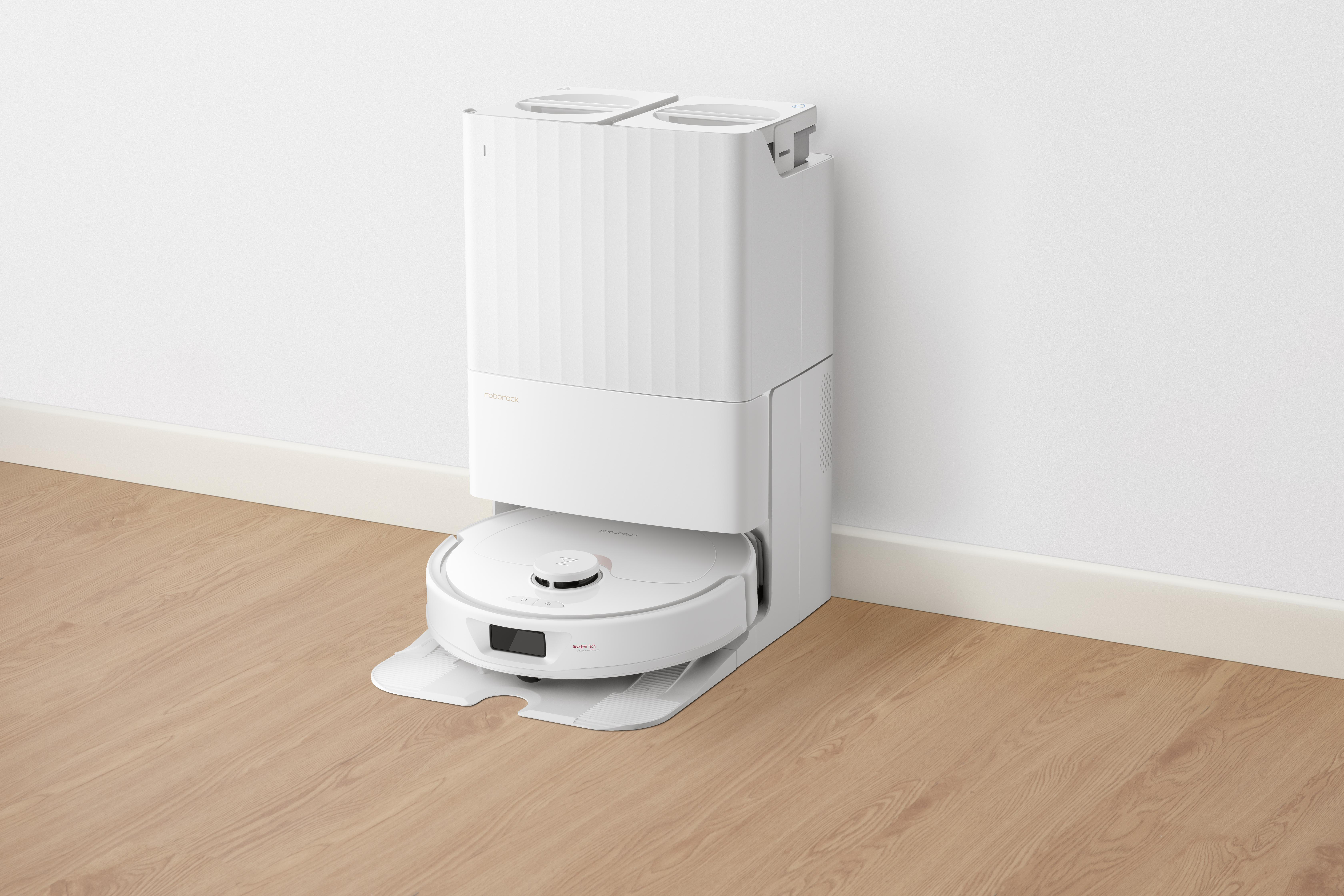Weißer Roboter-Staubsauger mit Ladestation. Der Boden ist Holz. Die Wände sind weiß.
