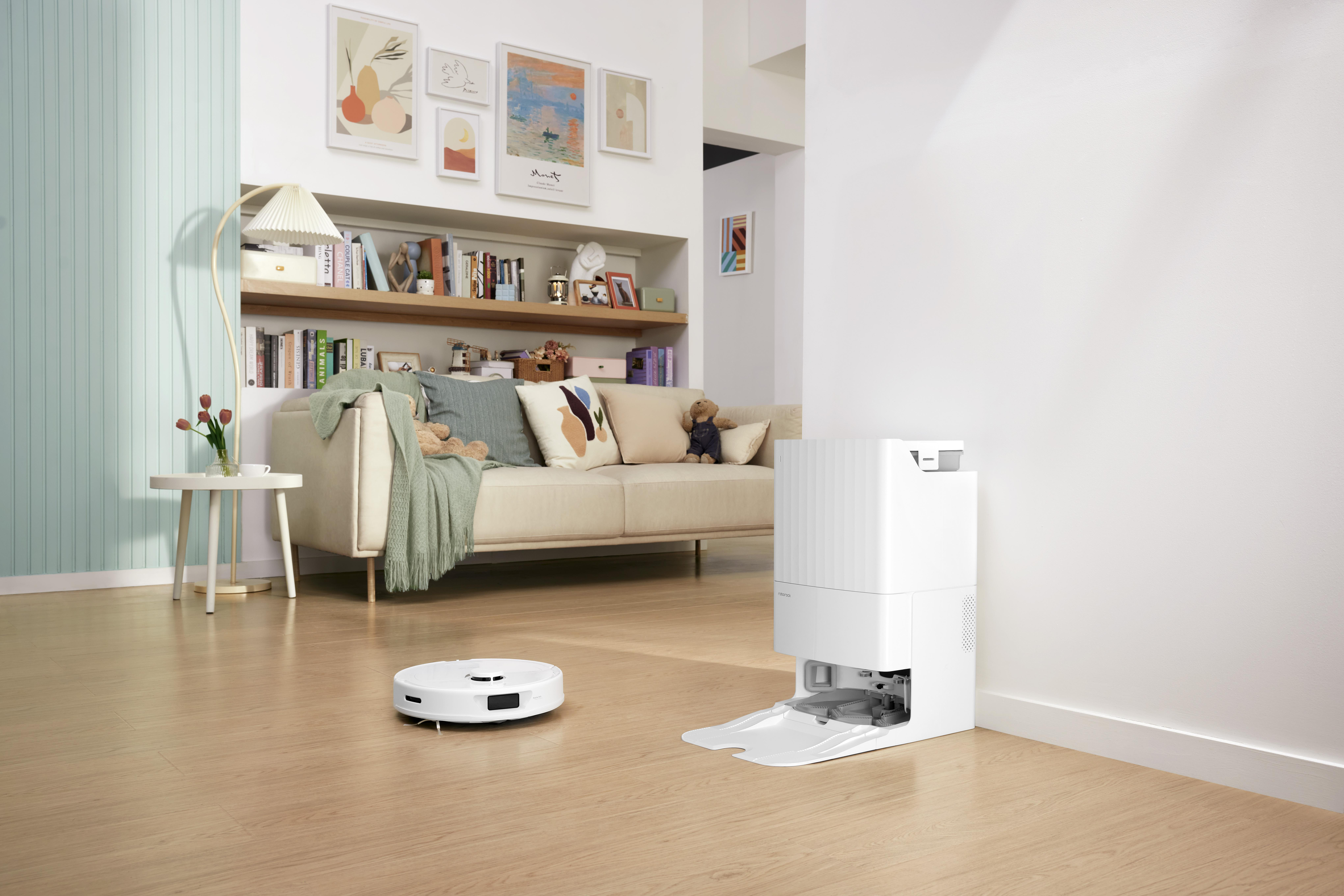 Ein modernes Wohnzimmer mit einem Roboter-Staubsauger, einer Ladestation und einem Sofa.