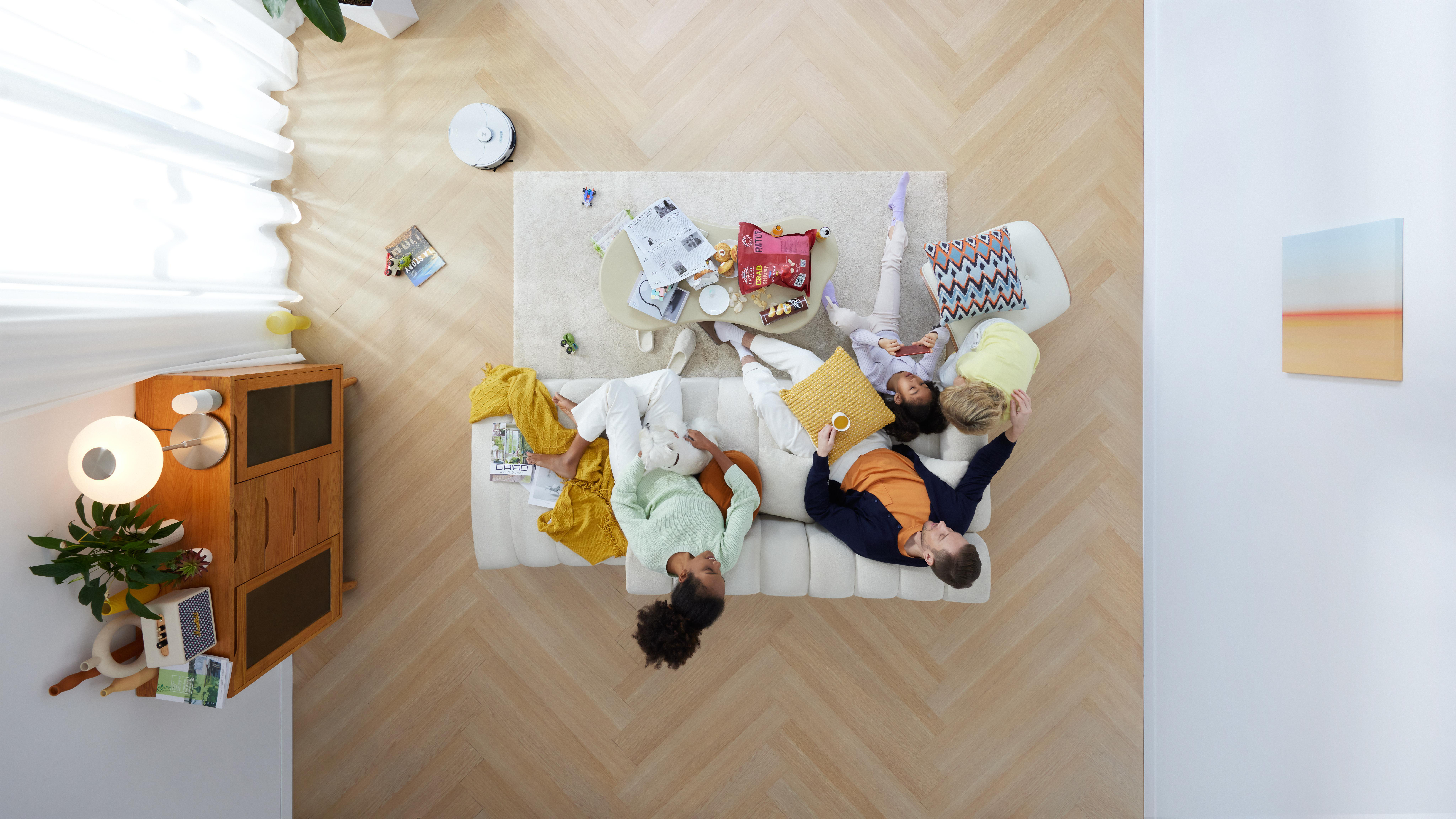 Menschen auf Sofa, Blick auf Couchtisch mit Gegenständen, Draufsicht.