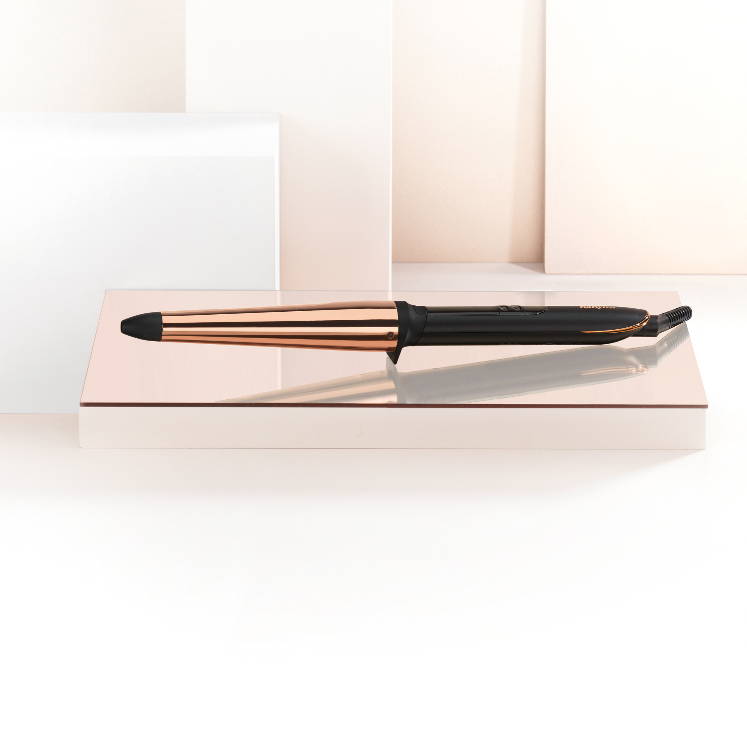 A rose gold and black curling iron on a rose gold stand.
