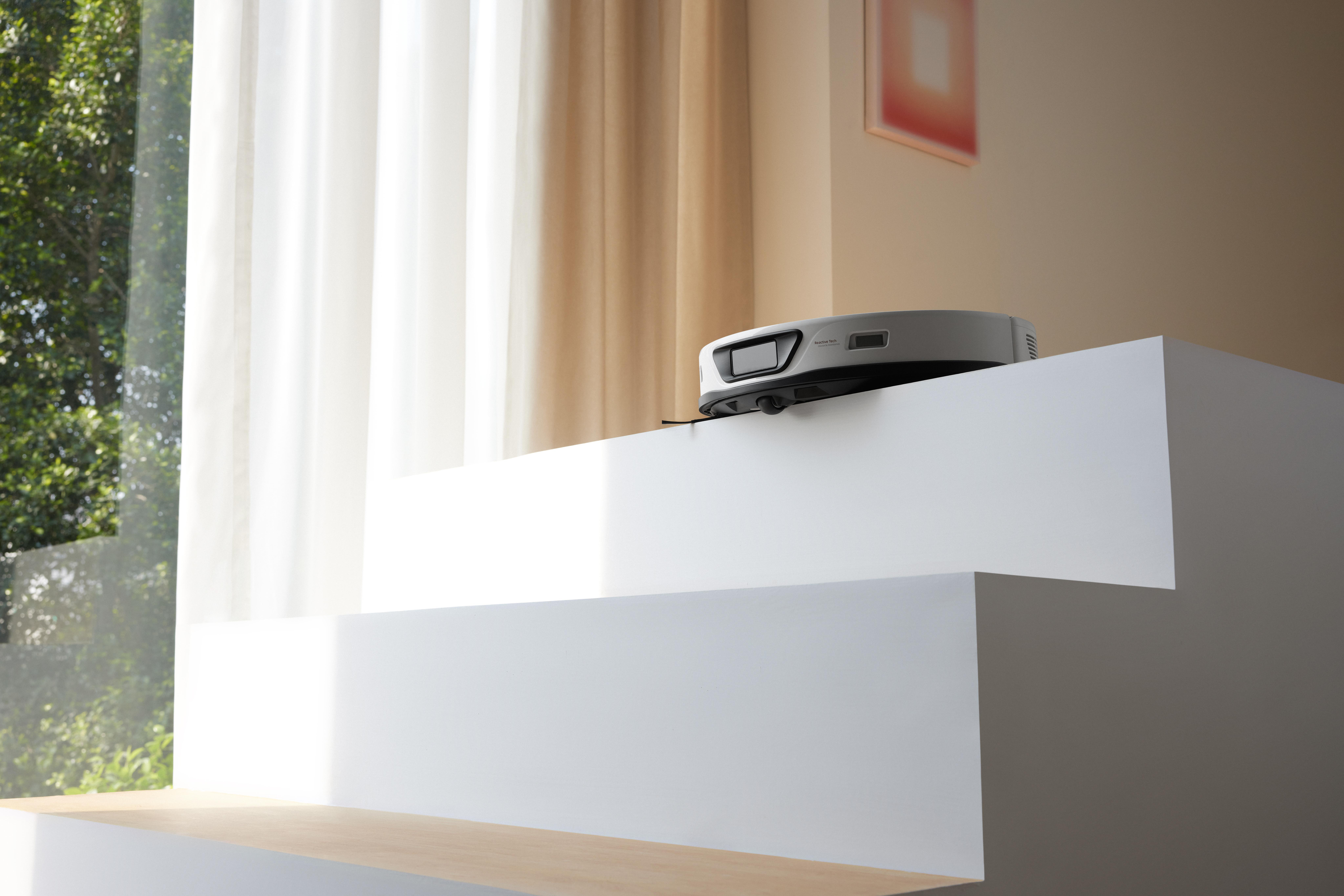 Roboter-Staubsauger auf weißen Stufen in der Nähe eines Fensters.