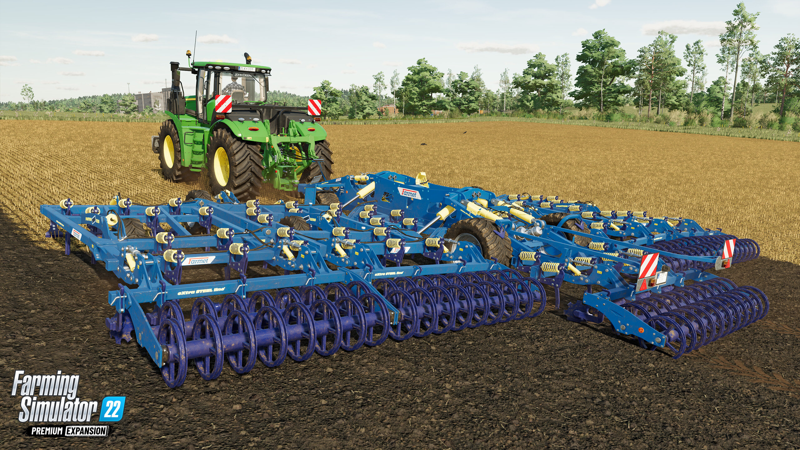 Traktor ciągnący niebieską maszynę rolniczą na polu. Logo 'Farming Simulator 22'.