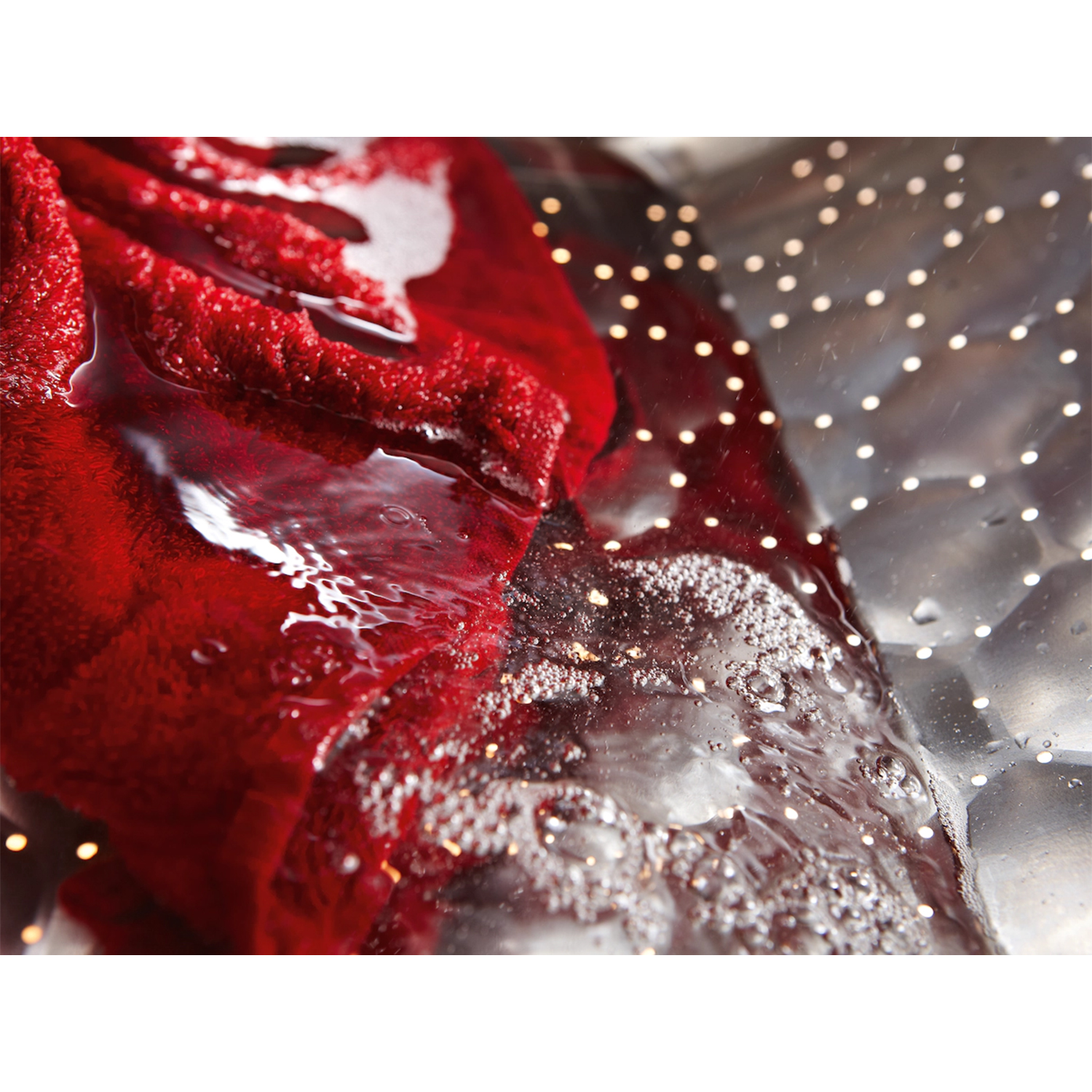 Tessuto rosso immerso nell'acqua, con bolle. L'acqua è pulita e il rosso risalta.