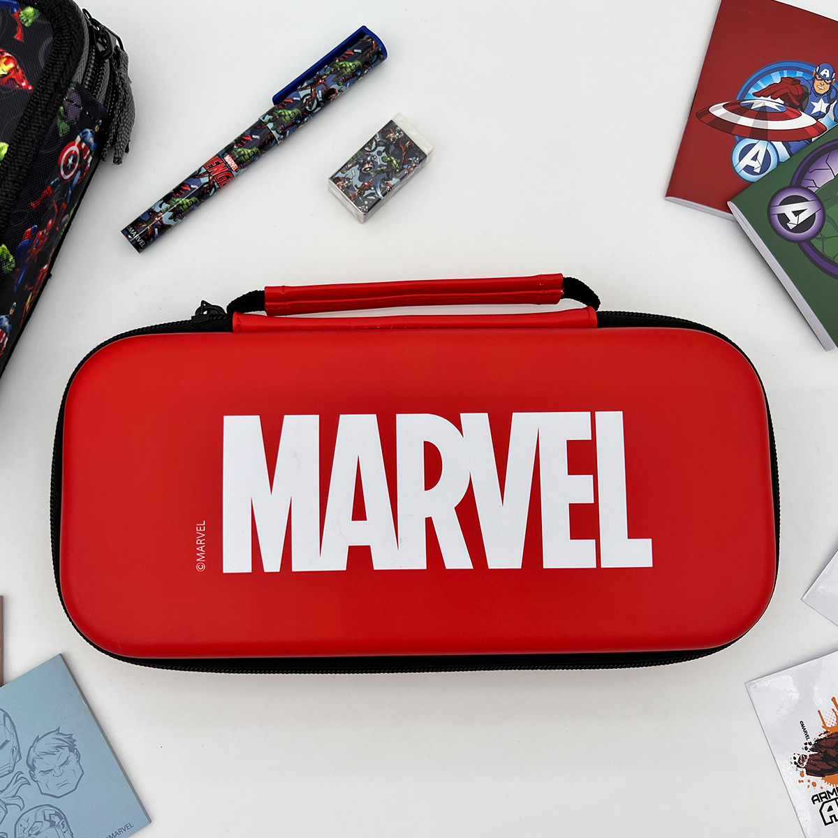 Estuche rojo de Marvel con el logo de Marvel, bolígrafo, borrador y cuadernos sobre fondo blanco.