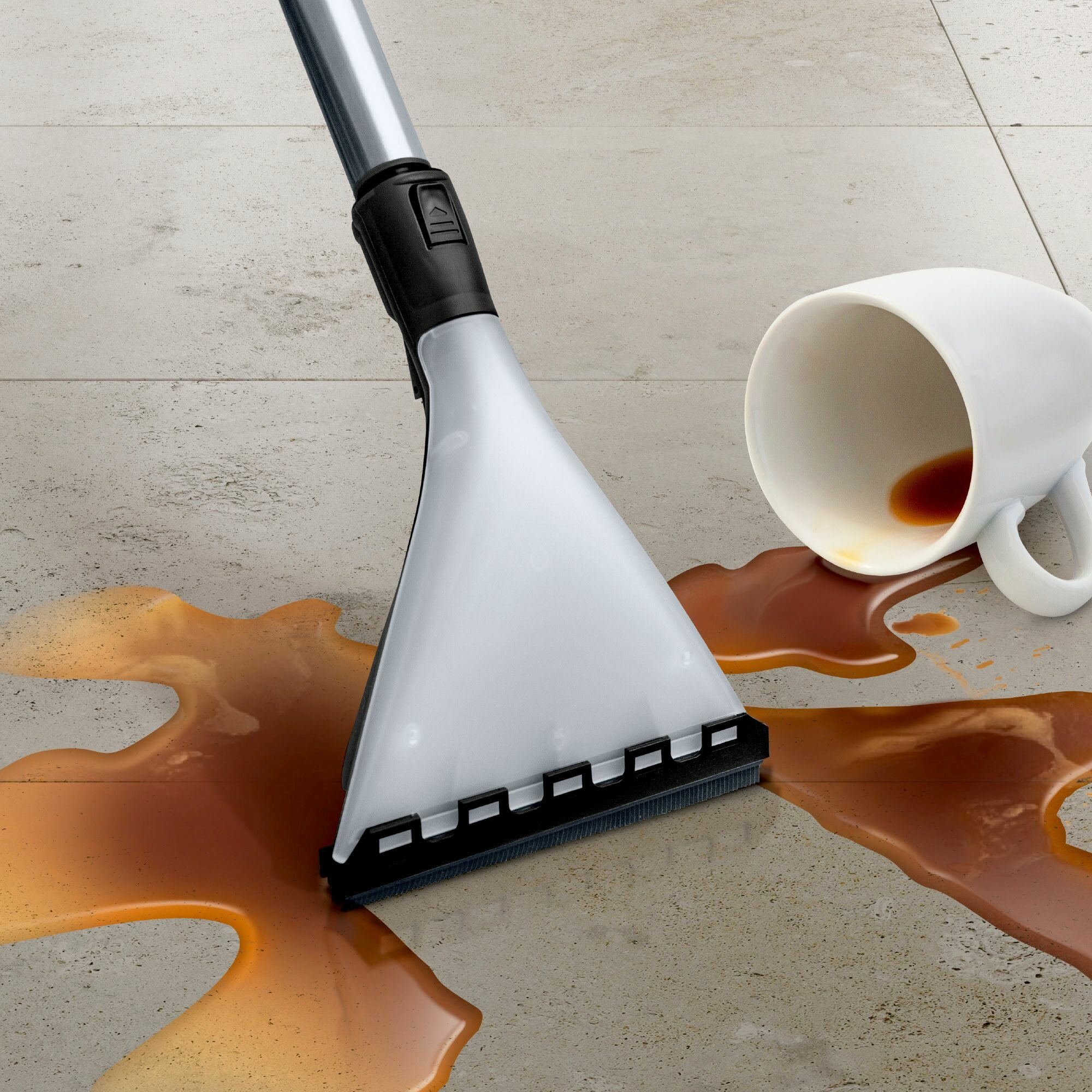 Głowica odkurzacza na podłodze z kafelkami z rozlaną kawą i białym kubkiem.