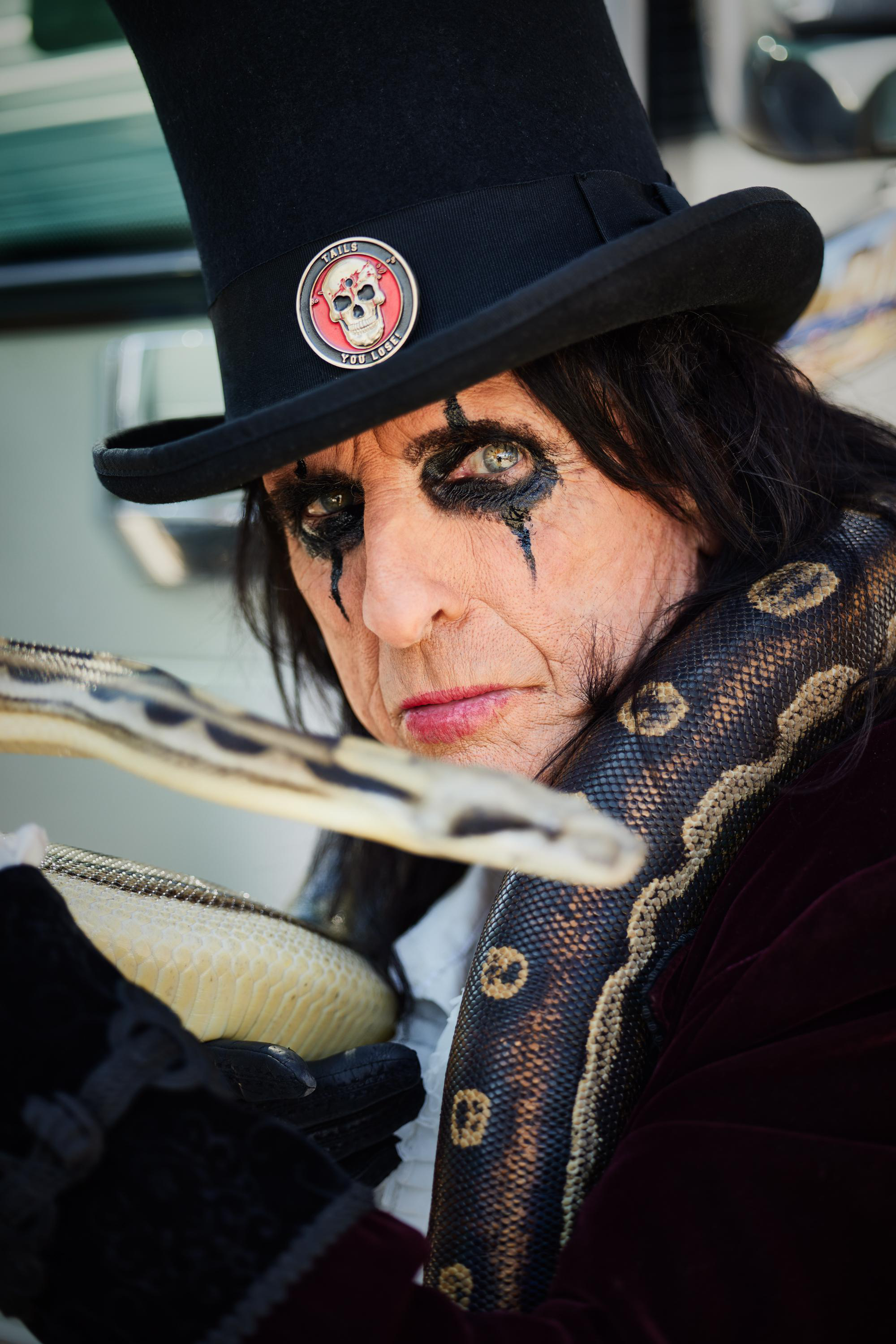 Alice Cooper hält eine Schlange und trägt einen Zylinder.