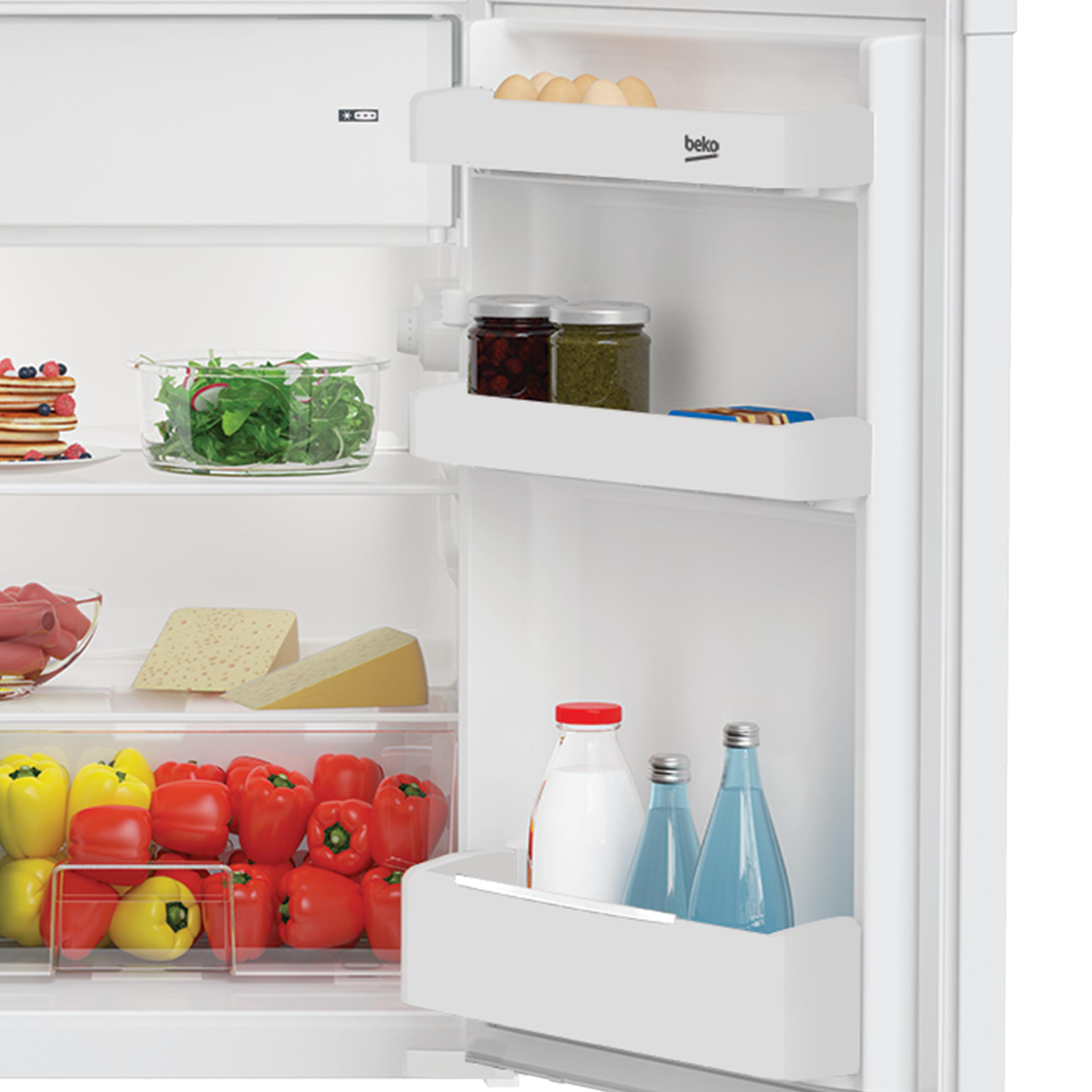 Innerhalb eines Kühlschranks, der Regale mit Milchprodukten, Gemüse und Waren in Gläsern zeigt.